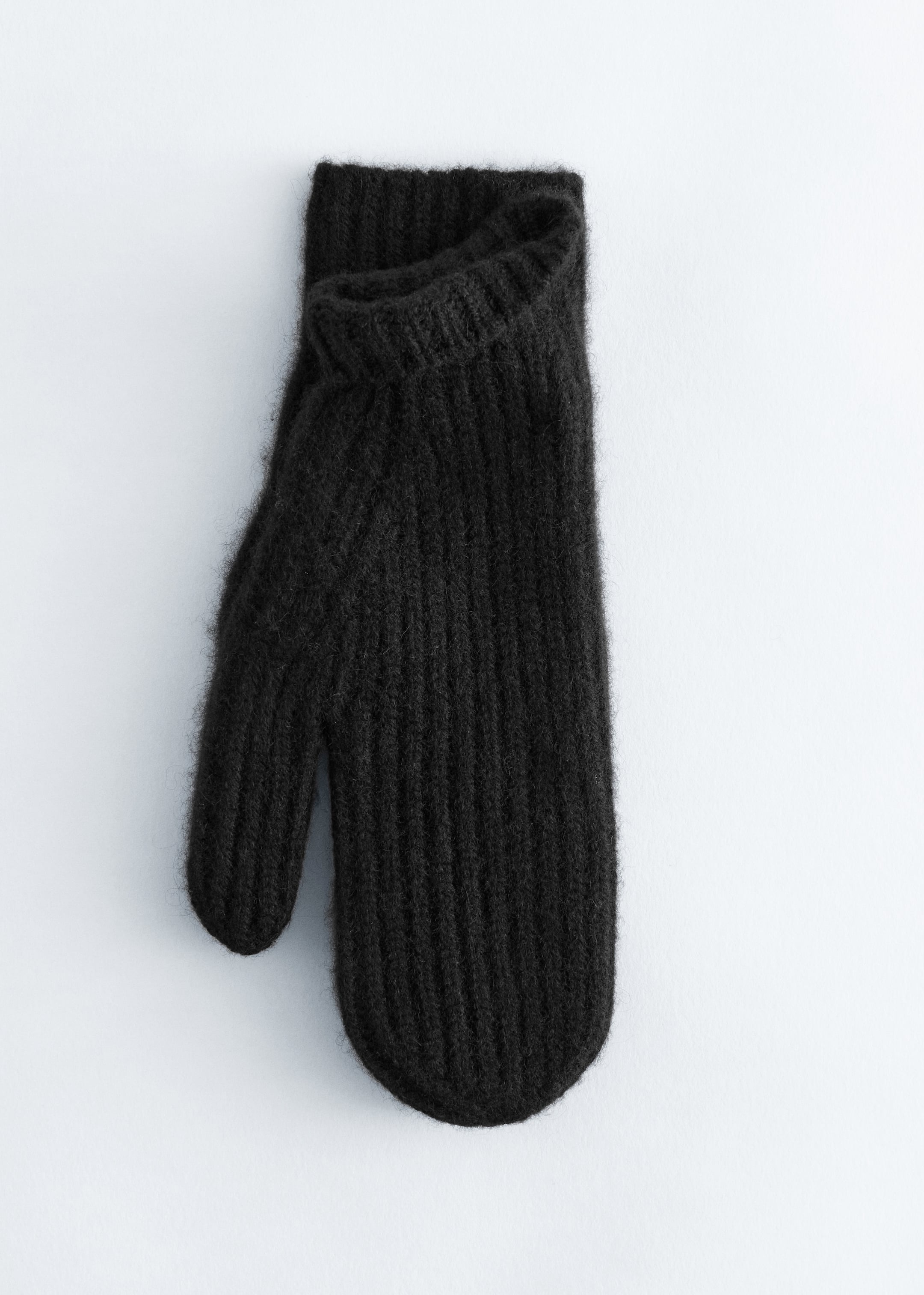 Visa större bild: En svart stickad vante presenteras med framsidan mot FRAM. Den har en framträdande vertikal ribbad struktur som täcker dess kropp och tumme, med en något vikt ribbad mudd.