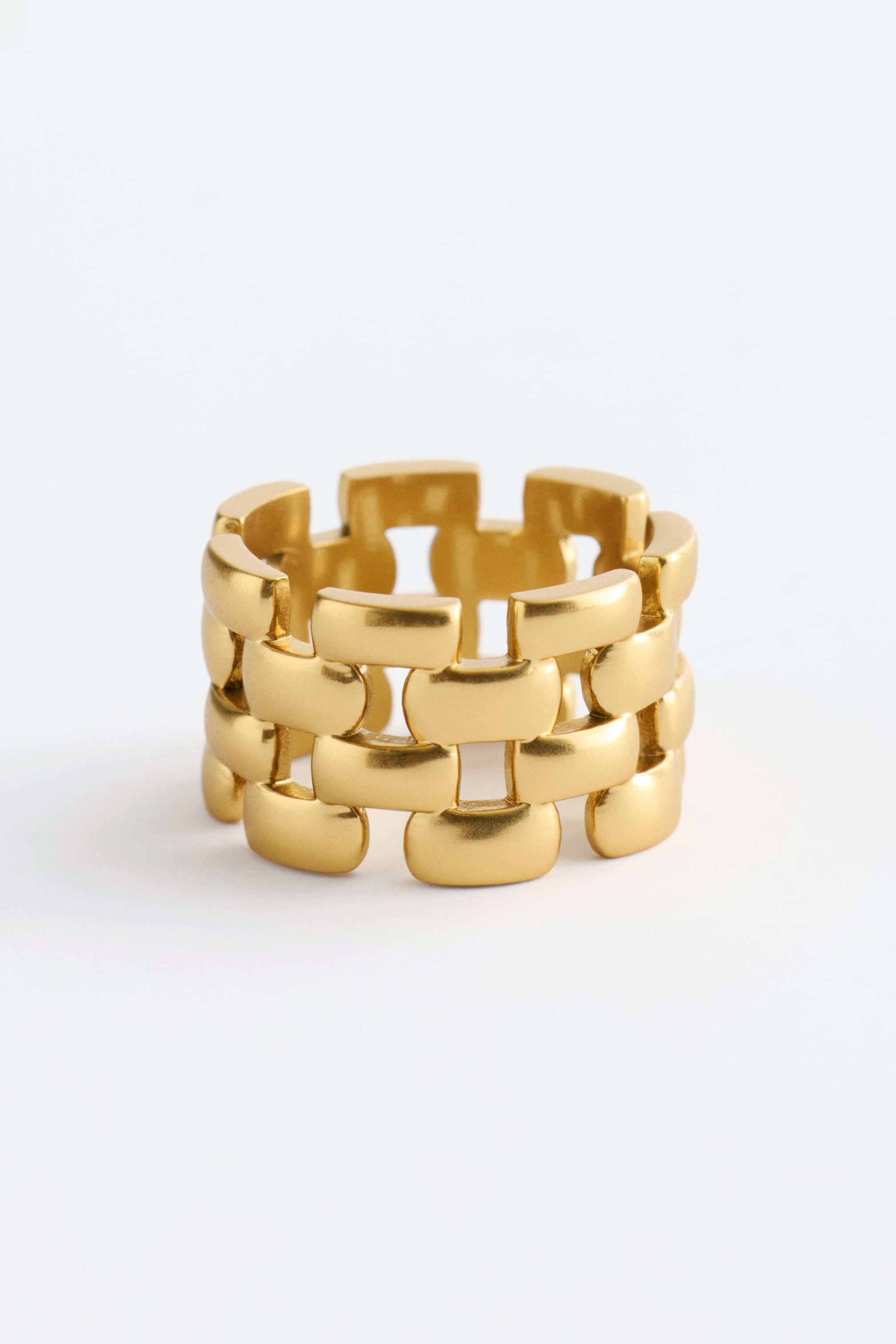 Agrandir l'image: Une bague imposante, fabriquée en laiton poli, présente un motif de chaîne architecturale. Elle est composée de carrés entrelacés, visibles sous un angle avant légèrement surélevé.