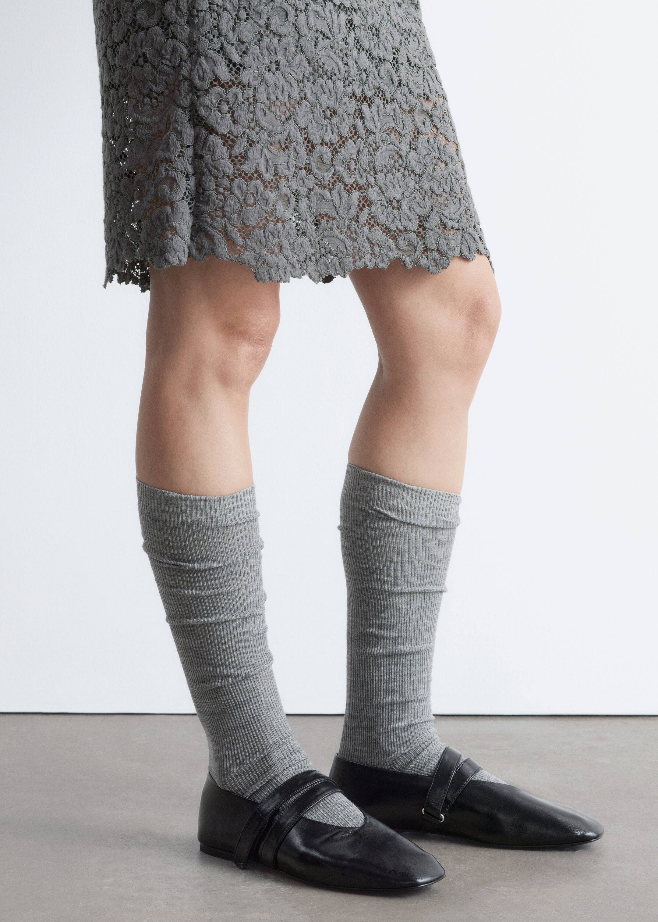 Преглед на по-голямо изображение: Сиви рипсени чорапи са носени намачкани надолу по прасците на модела. Черни обувки тип "Мери Джейн" с остър връх и двойни каишки на подметката са носени върху чорапите, под сива дантелена пола.