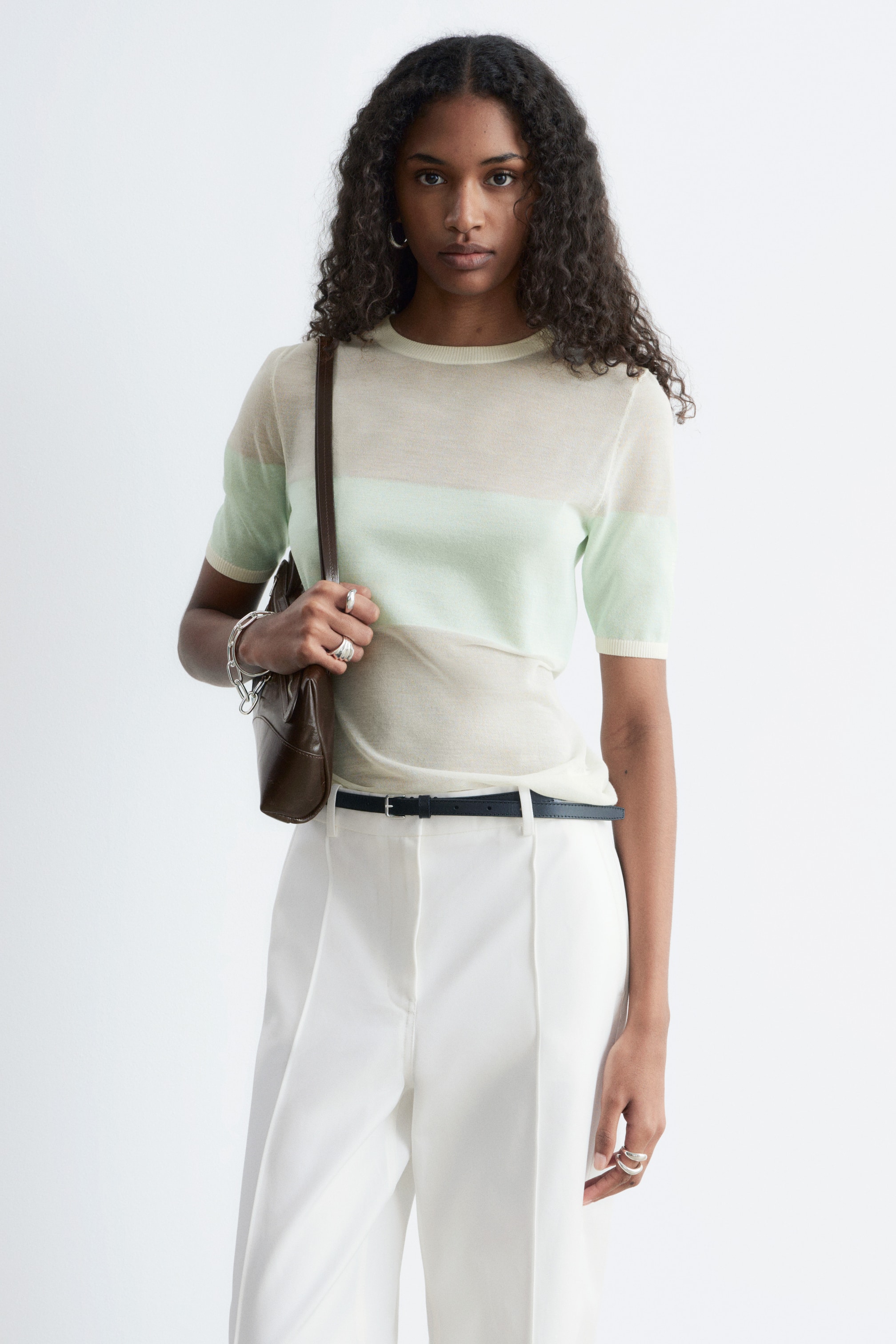 View larger image: A slim-fit, short-sleeved knitted top showcasing a colour-block pattern of sheer light cream and light mint green horizontal bands. It is designed with a ribbed crew neck and ribbed cuffs.