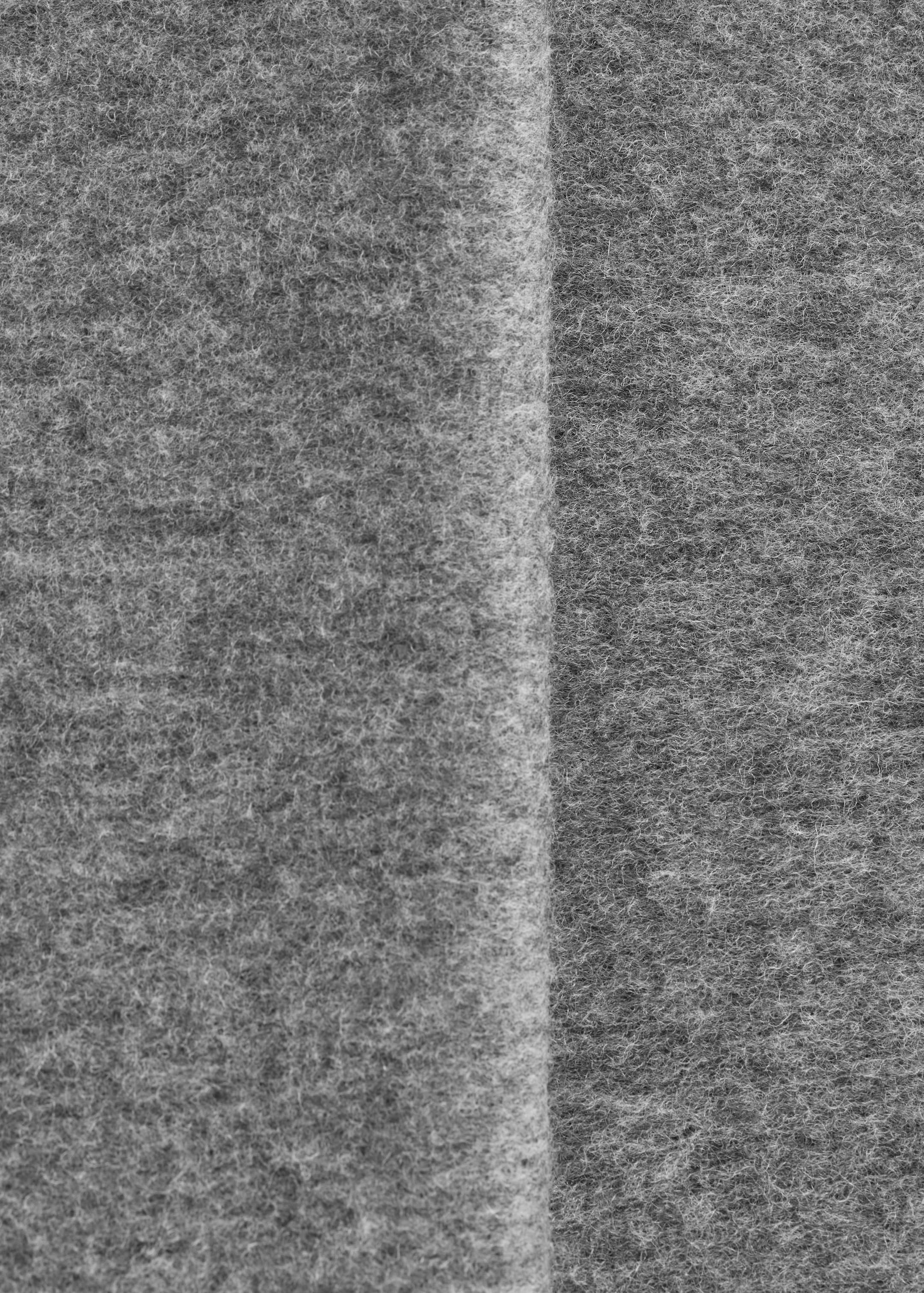 Visa större bild: Den grå ylleschalen visar en mjuk, luddig textur, med en subtil vertikal veck synlig på ytan.