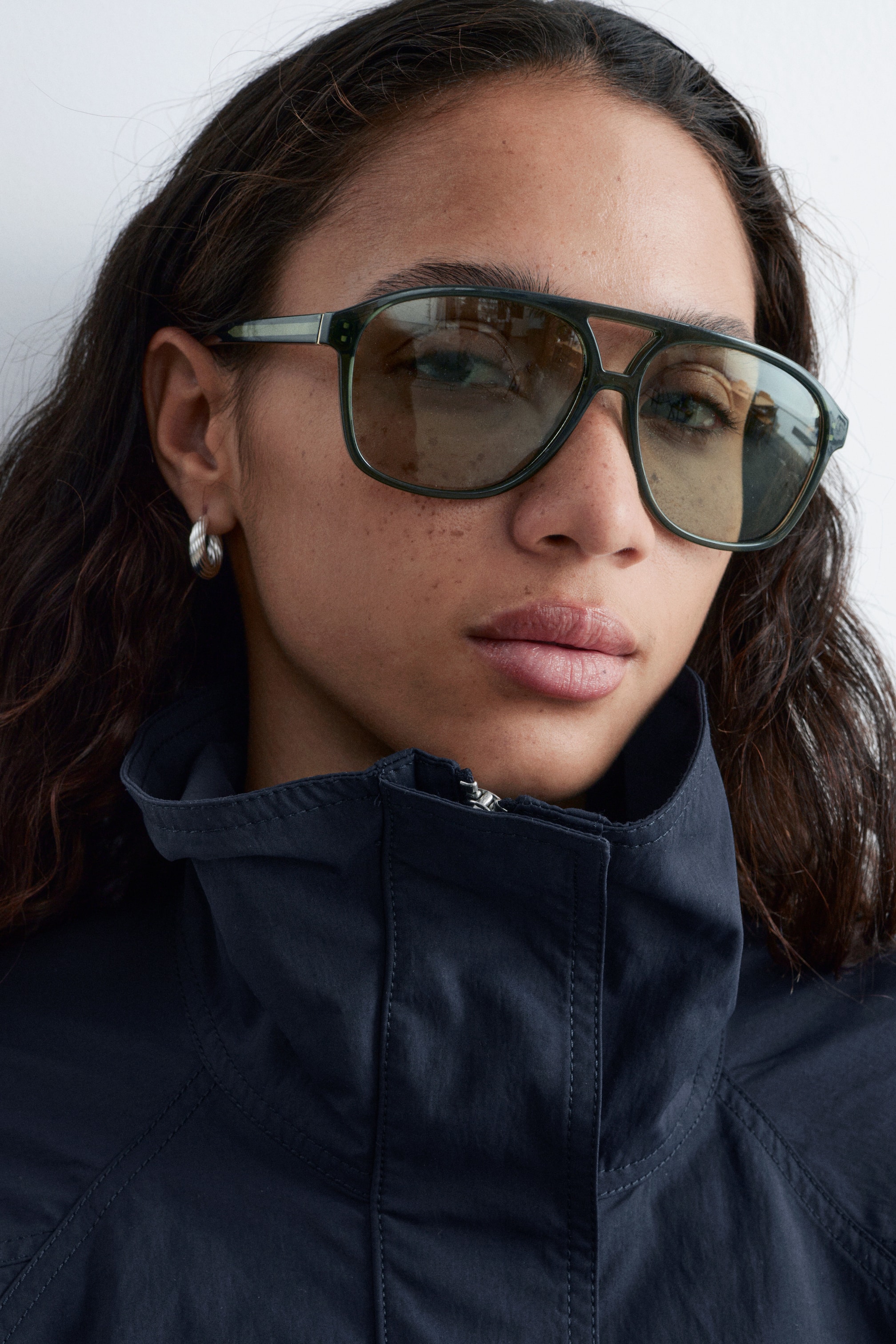 Vis større bilde: Oversized solbriller i aviator-stil, med mørkegrønne rammer med avrundede kanter, en klassisk brynbøyle, slanke stenger og tonede linser, bæres av modellen.