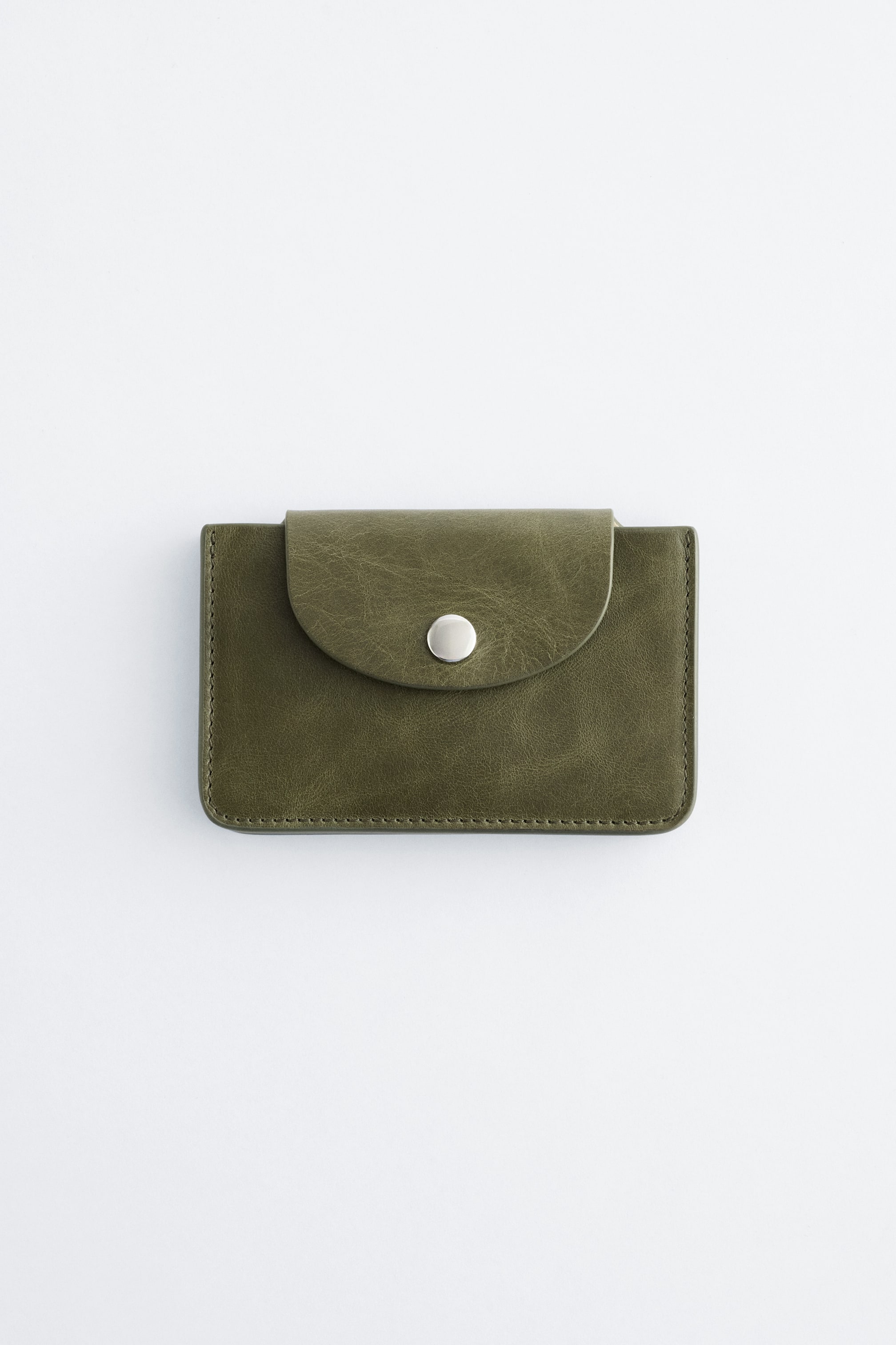 Visualizza immagine più grande: Un portatessere verde oliva è posizionato frontalmente, caratterizzato da una patta arrotondata con chiusura a pressione argentata e cuciture visibili lungo i bordi.