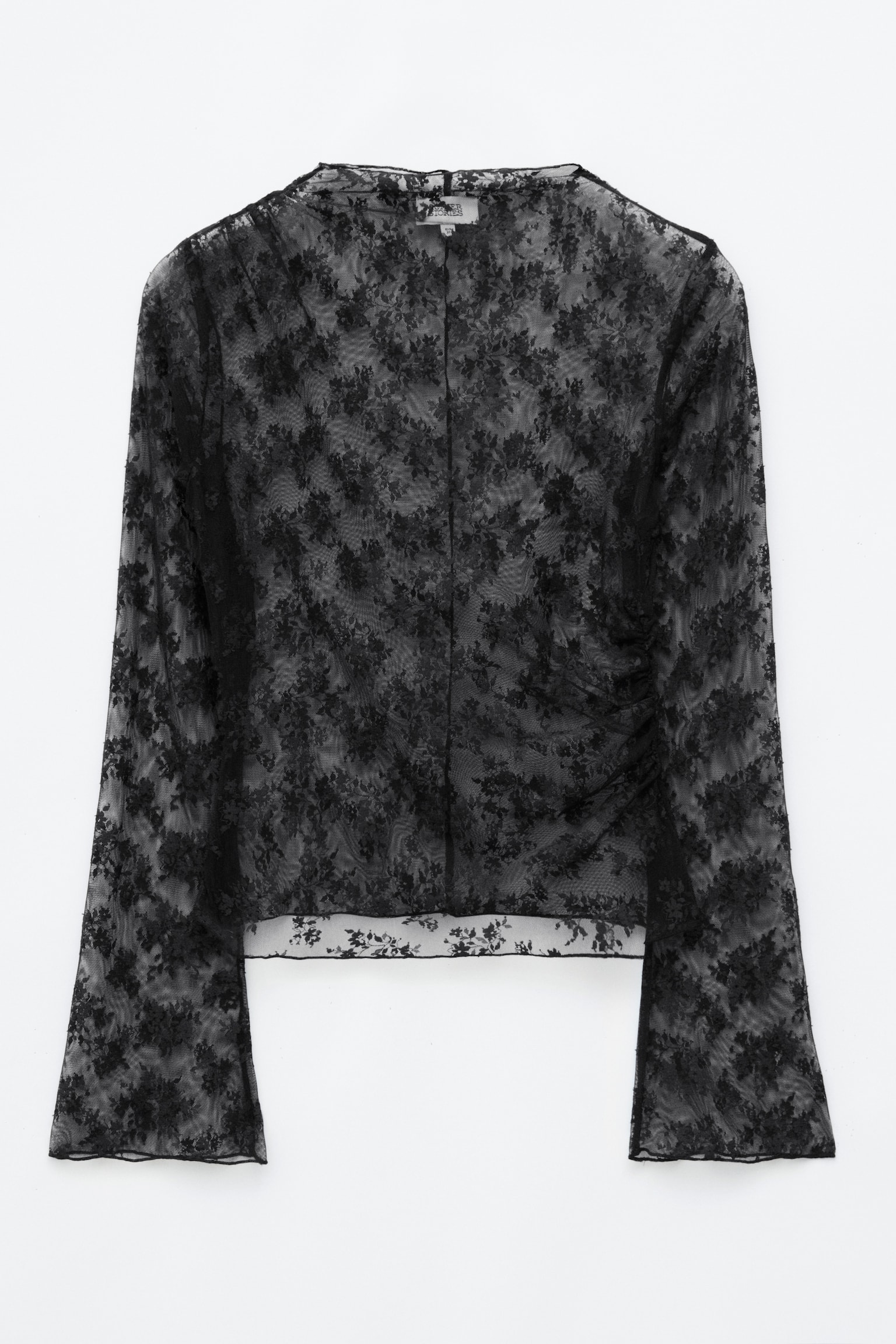 Un top negru din dantelÄ este orientat spre faÈÄ, evidenÈiind un model floral transparent, guler tip mock neck Èi mâneci lungi evazate cu margini baby lock. Topul prezintÄ fronsare asimetricÄ la un umÄr Èi pe cusÄtura lateralÄ opusÄ, creând o siluetÄ drapatÄ.
