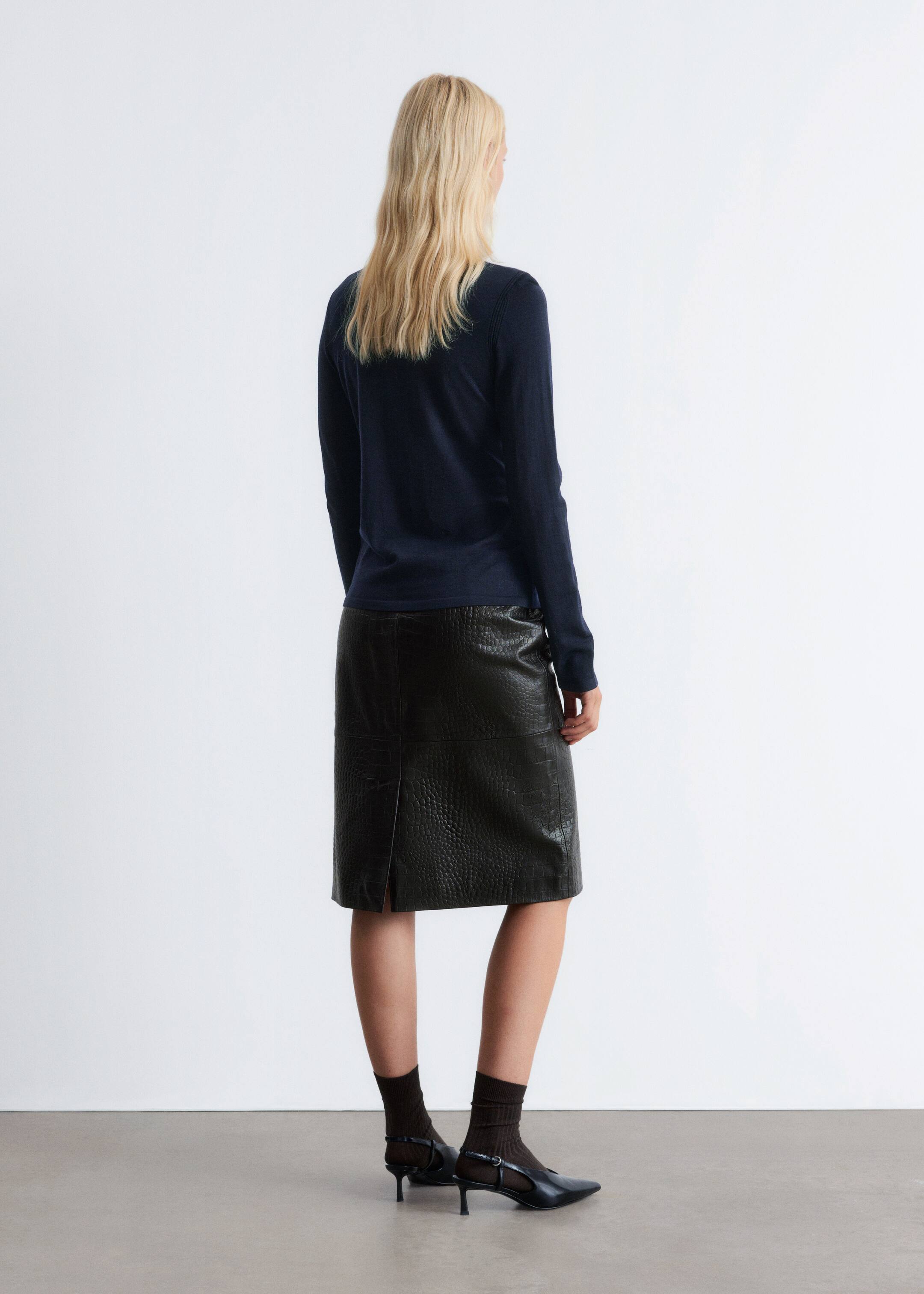 View larger image: A dark, straight, knee-length skirt, featuring an embossed crocodile-effect texture and a central back vent, is being worn from a back view.