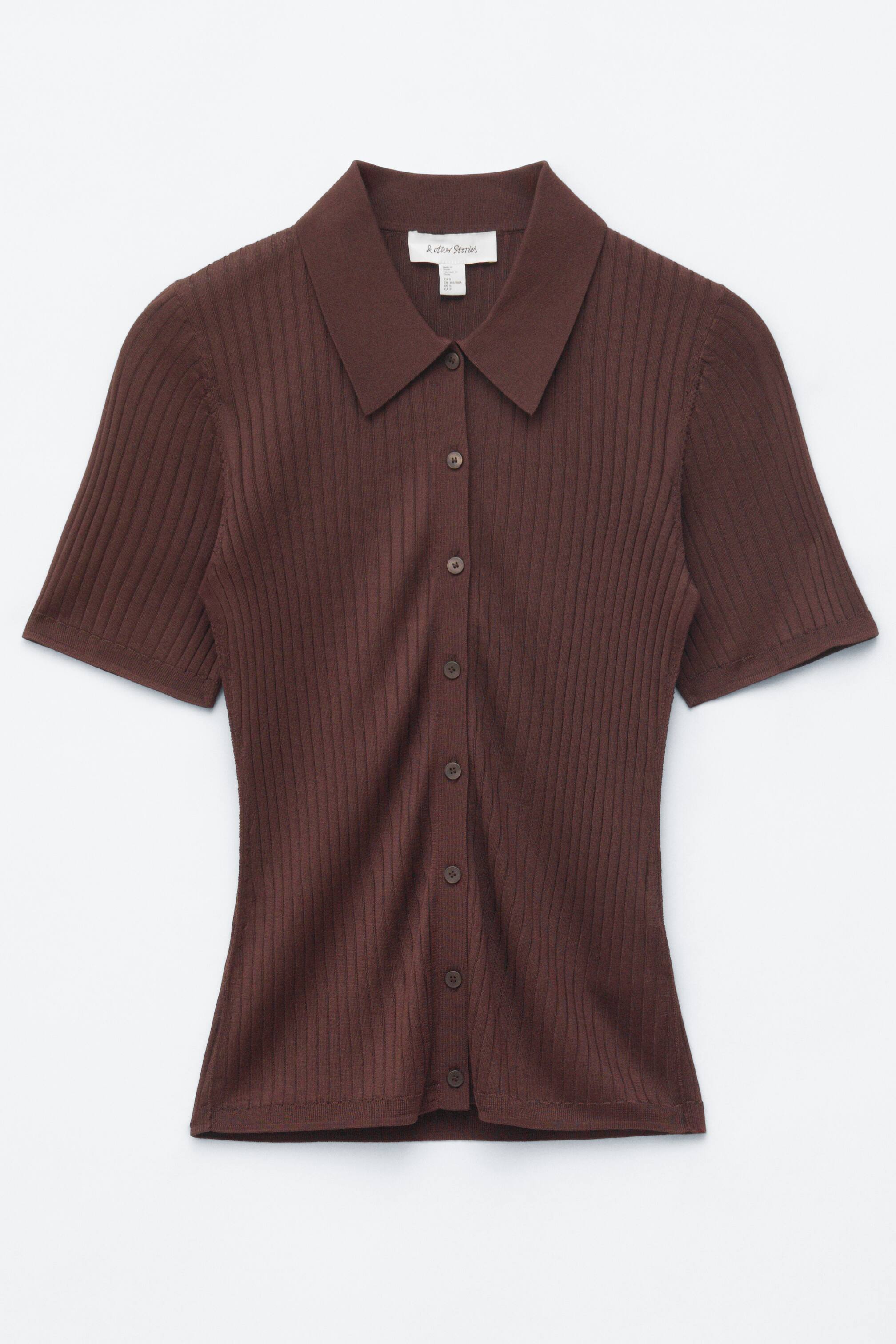 הצגת תמונה גדולה יותר: חולצת פולו סרוגה בצבע חום מציגה את המראה הקדמי שלה, עם שרוולים קצרים, צווארון פולו ופתח כפתורים עם שבעה כפתורים תואמים בצבע חום.