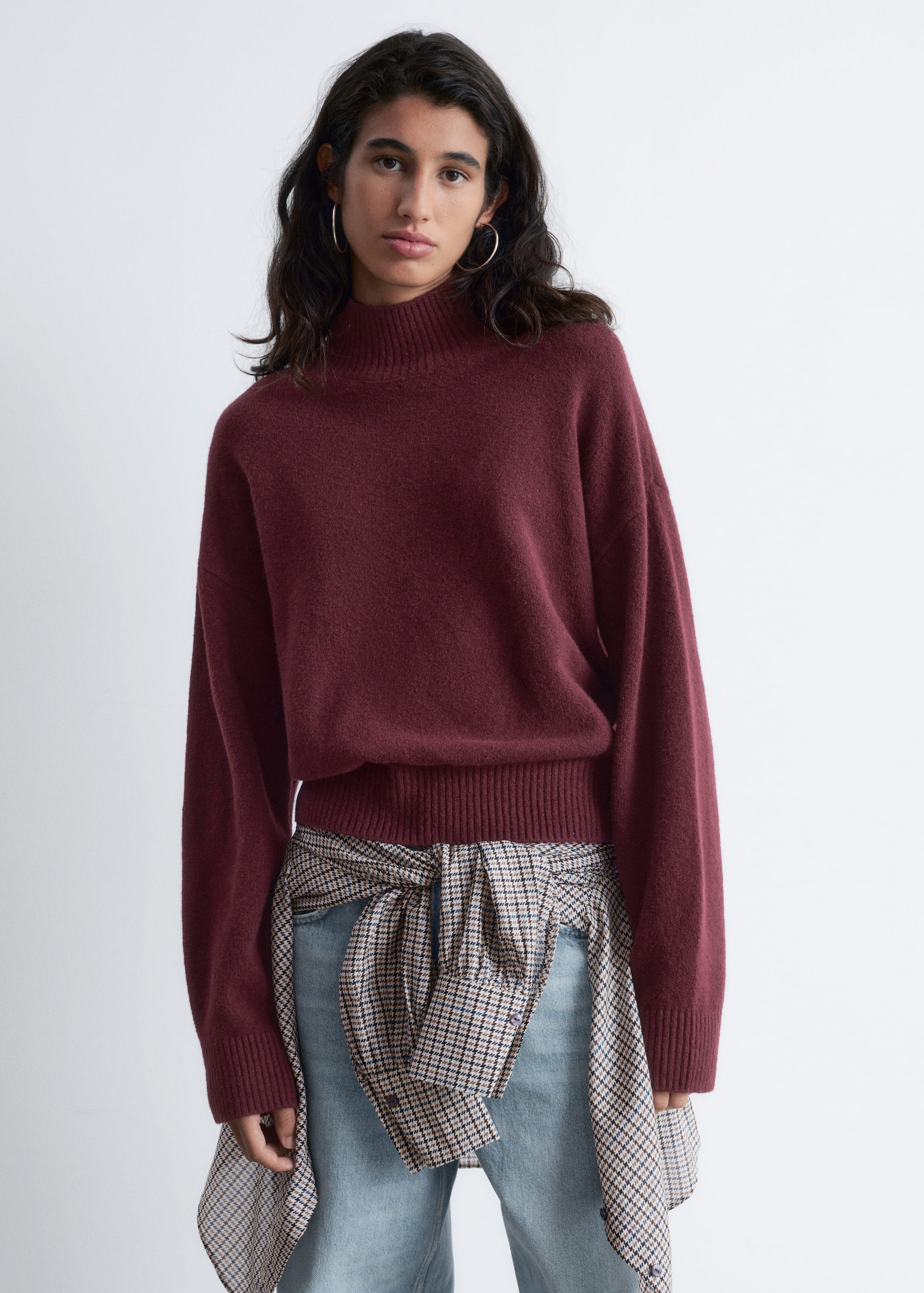 Größeres Bild anzeigen: Ein bordeauxroter Strickpullover wird ausgestellt, leicht nach vorne gerichtet. Er verfügt über einen Stehkragen und lange Ärmel, die in gerippten Bündchen enden, während er mit seinem gerippten Saum, der leicht an der Taille anliegt, eine lockere Passform zeigt.