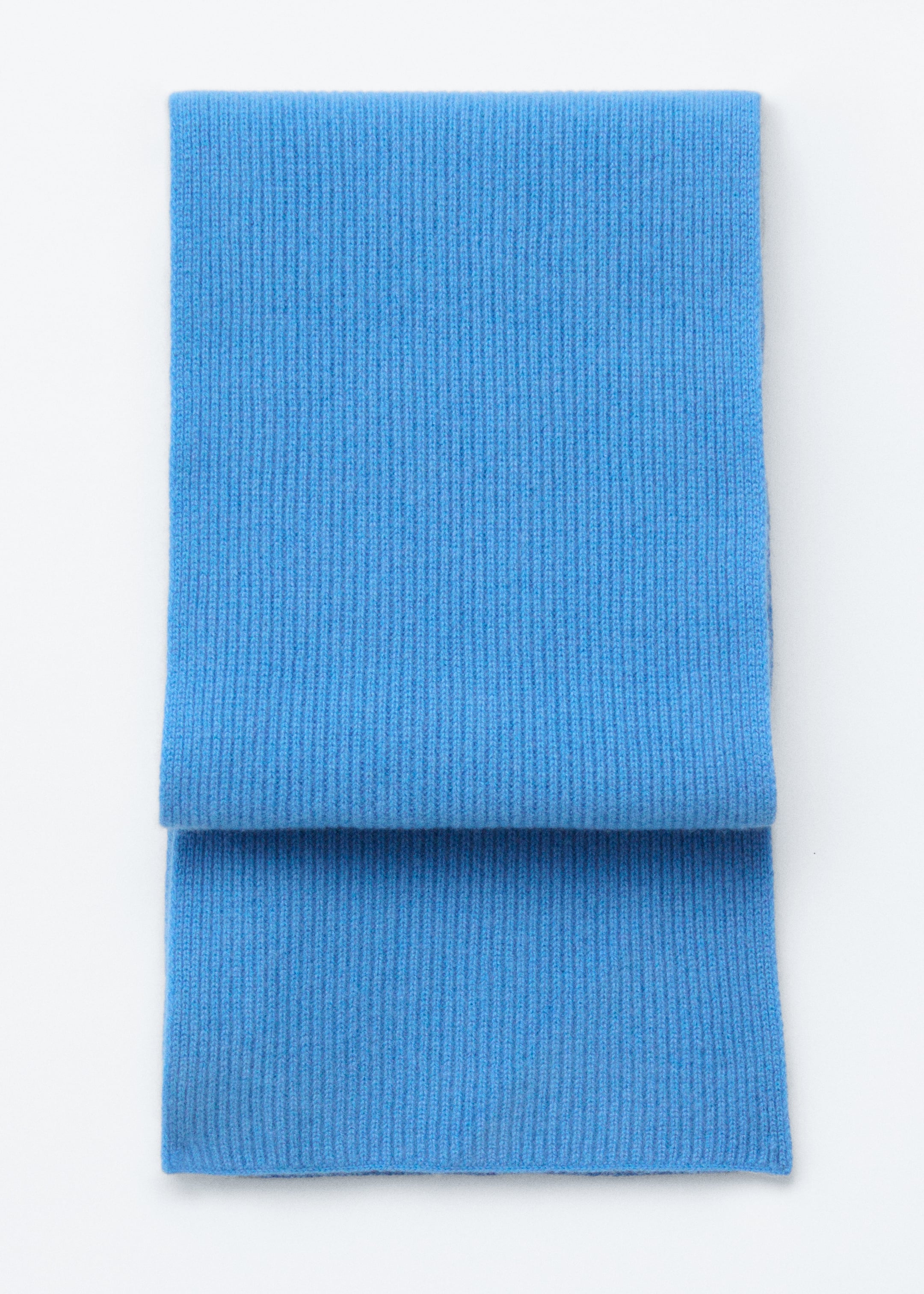 Visa större bild: En blå stickad halsduk med ribbad finish ligger platt, vikt över sig själv.