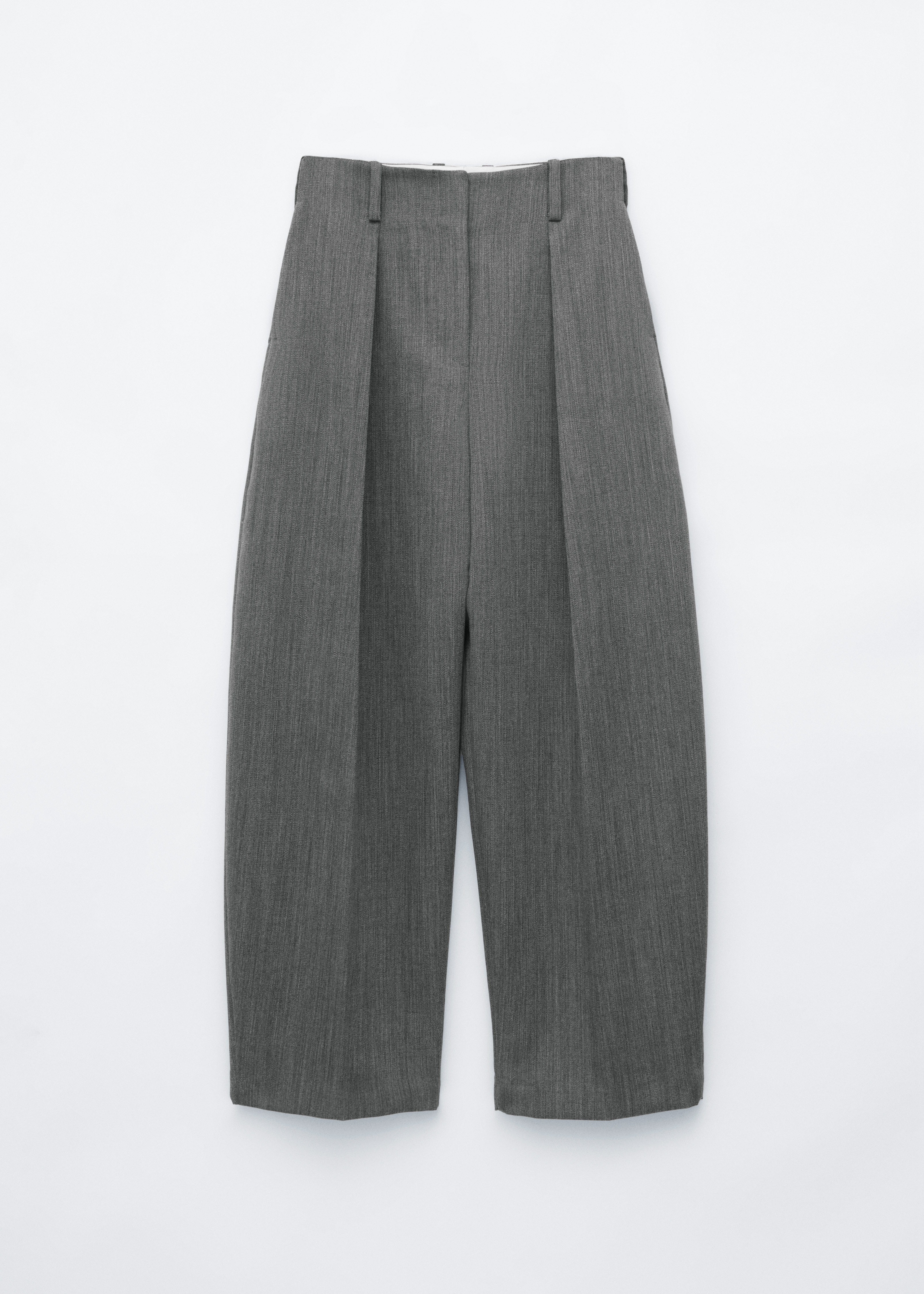 Le mannequin porte un pantalon en laine gris Ã  silhouette barrel leg et avec des plis marquÃ©s. Ce pantalon taille haute est associÃ© Ã  une ceinture en cuir noir, Ã  un pull col roulÃ© rouge vif et Ã  un blazer gris assorti.