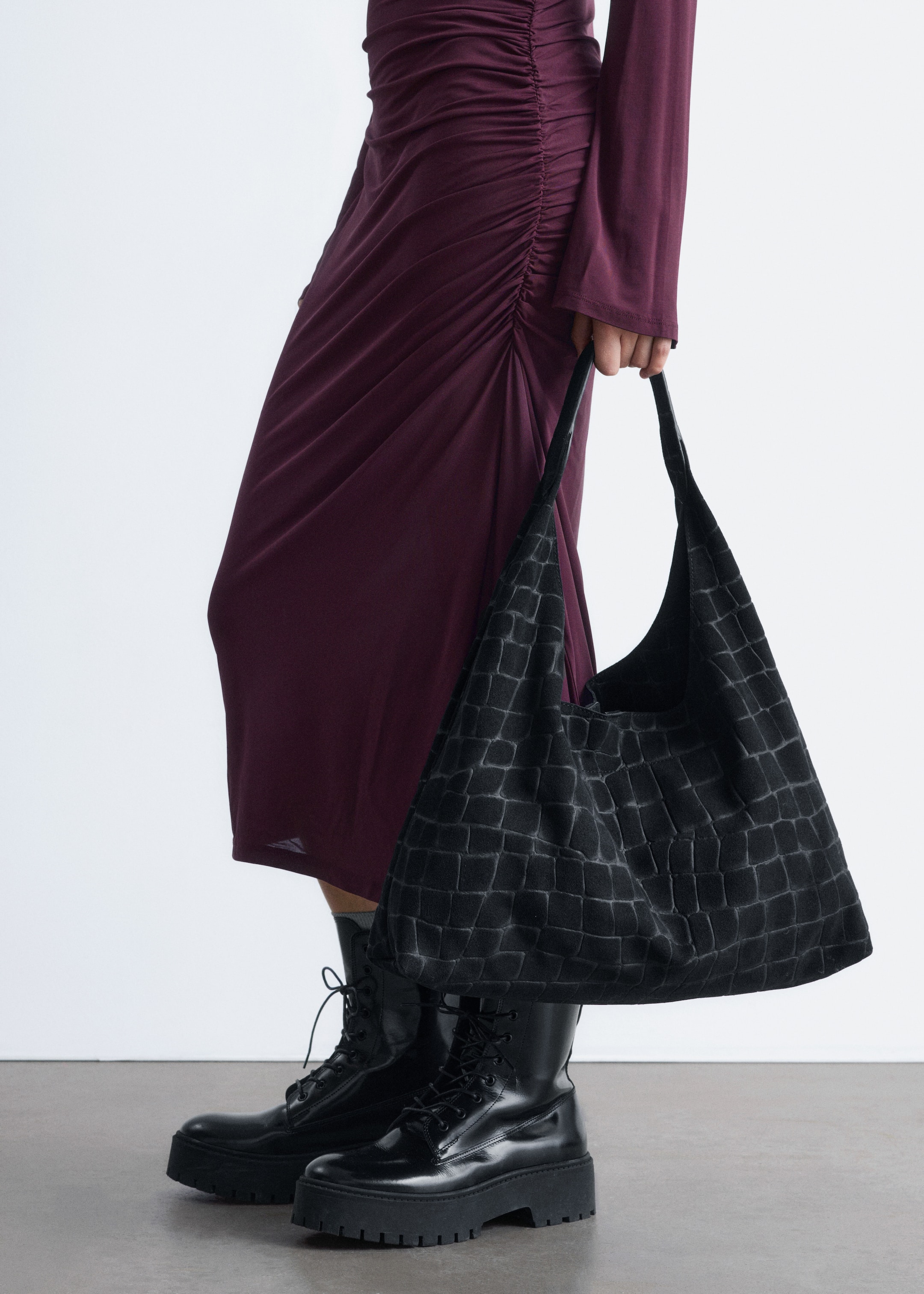 Größeres Bild ansehen: Eine schwarze Hobo-Tasche wird gehalten, ihr weicher, unstrukturierter Körper zeigt ein tiefgeprägtes Krokodil-Embossing-Muster auf der Vorderseite und verfügt über zwei breite, weiche Träger.