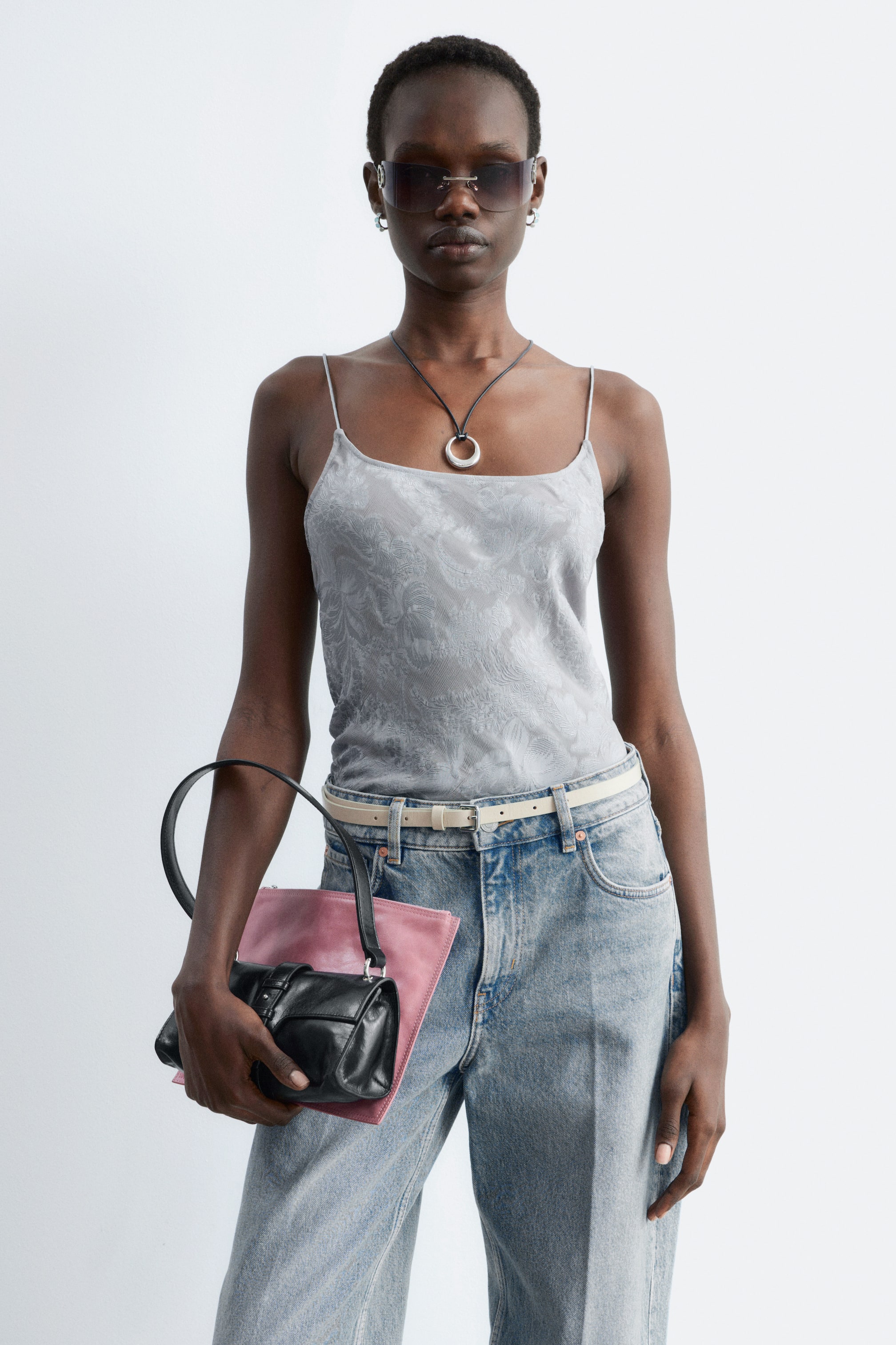 Visualizza immagine più grande: Un top canotta grigio presenta un motivo tonale sottile su tutta la superficie, con sottili spalline a spaghetti e una scollatura dritta, indossato frontalmente.