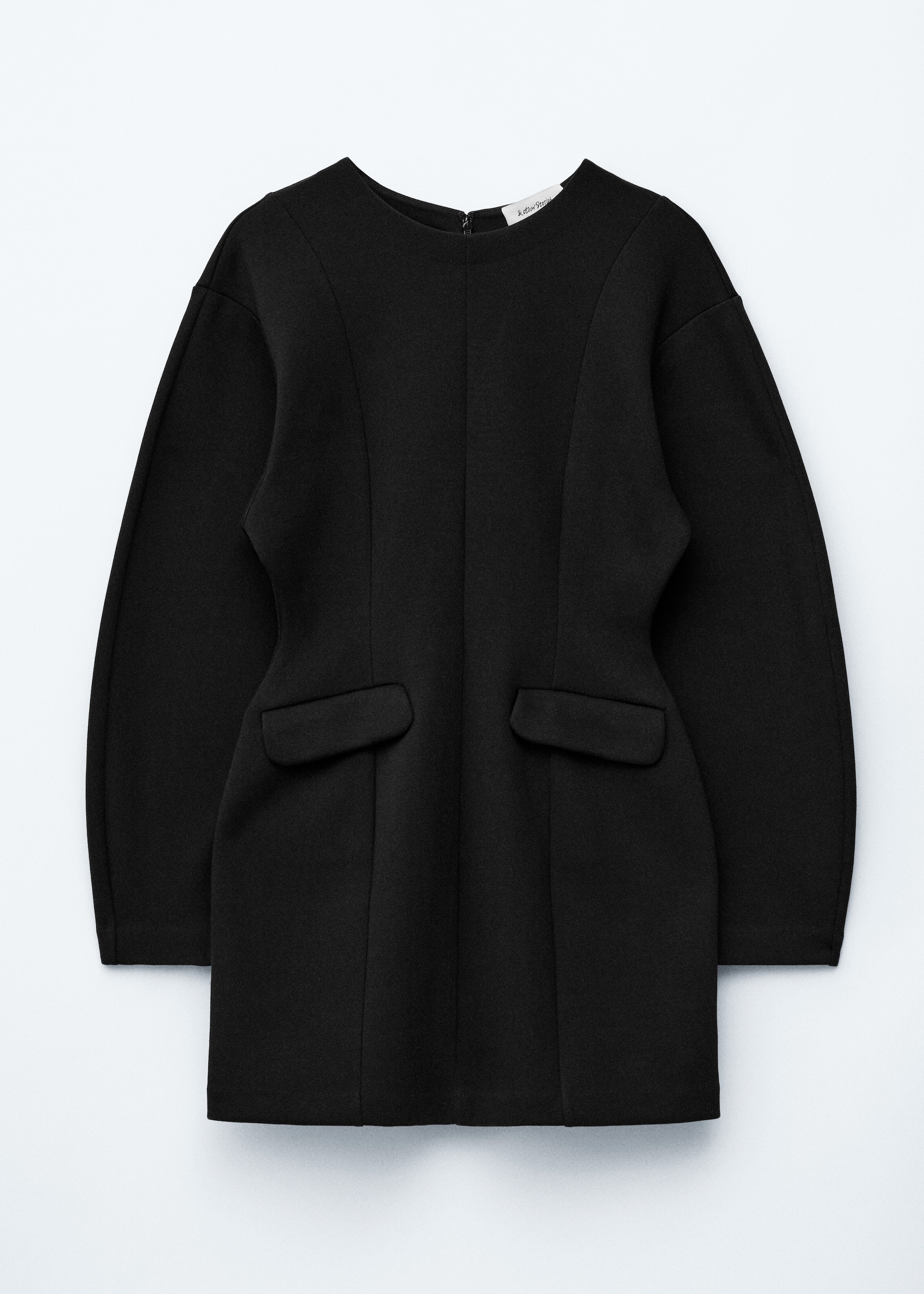 Visualizza immagine più grande: Un mini abito nero è esposto frontalmente, caratterizzato da uno scollo rotondo, maniche lunghe con spalle scese e cuciture verticali che modellano il corpetto. Due grandi tasche con patta rettangolare sono posizionate sulla parte inferiore anteriore.