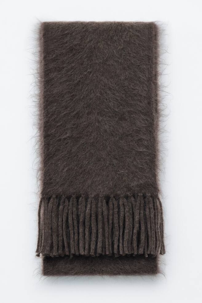 A dark brown mohair-wool blend scarf is laid flat in a front view, showcasing a fuzzy, brushed texture with soft halo fibres along its edges. The neatly folded scarf displays thick, twisted fringe tassels at the bottom edge. - 1