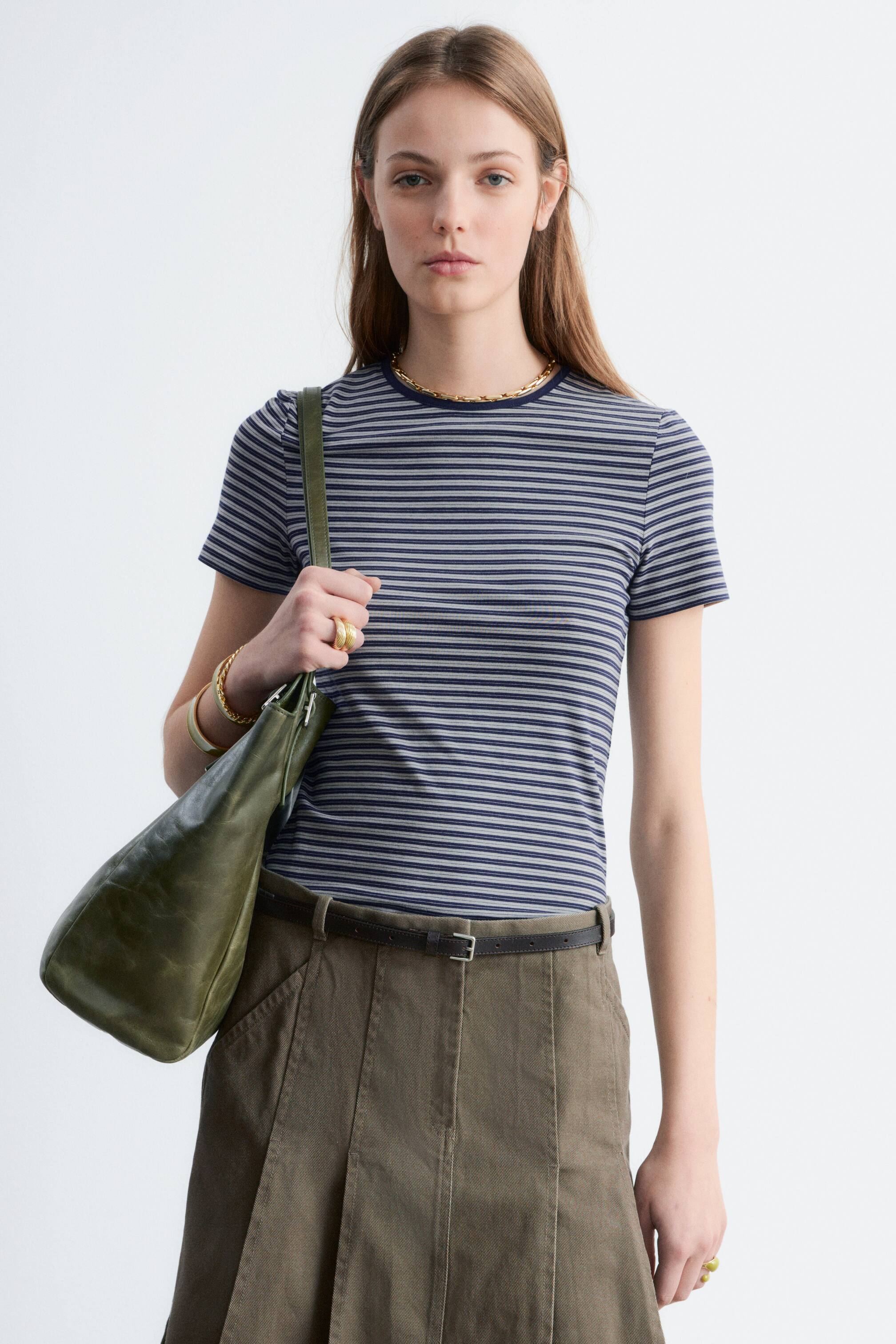 Ver imagen más grande: Una camiseta de manga corta presenta rayas horizontales en azul marino y gris claro con cuello redondo. Se lleva puesta, de frente, mostrando su diseño ajustado.