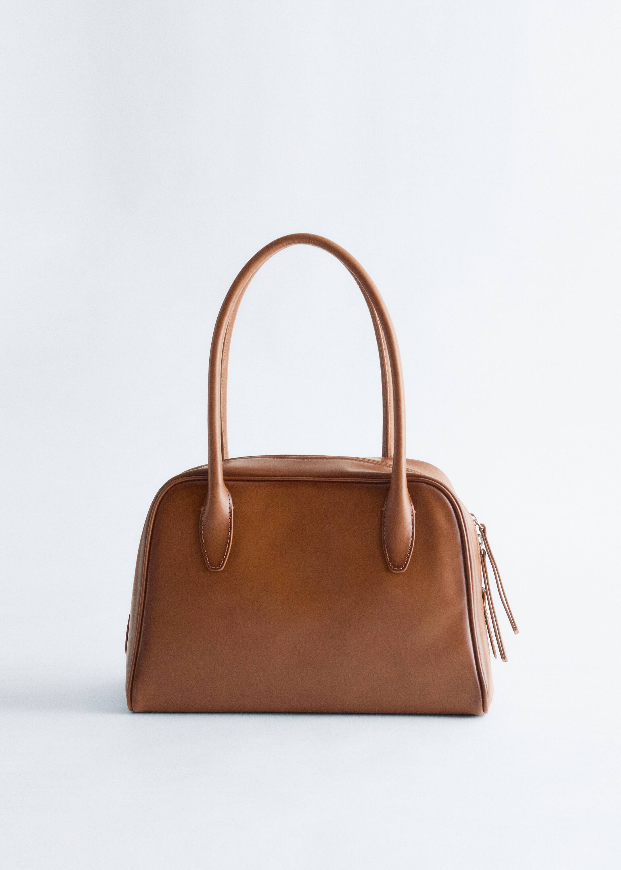 Grösseres Bild ansehen: Eine braune Handtasche wird von vorne präsentiert, mit einem strukturierten, glatten Körper und abgerundeten oberen Kanten, zwei oberen Griffen und einem sichtbaren oberen Reissverschluss mit Zippern.