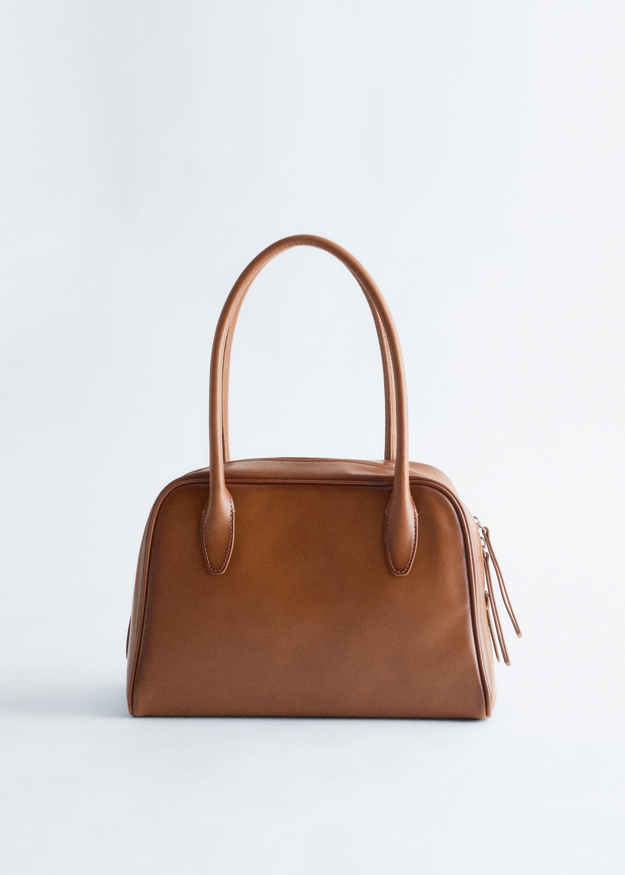 Größeres Bild ansehen: Eine braune Handtasche wird von vorne präsentiert, mit einem strukturierten, glatten Körper und abgerundeten oberen Kanten, zwei oberen Griffen und einem sichtbaren oberen Reißverschluss mit Zippern.
