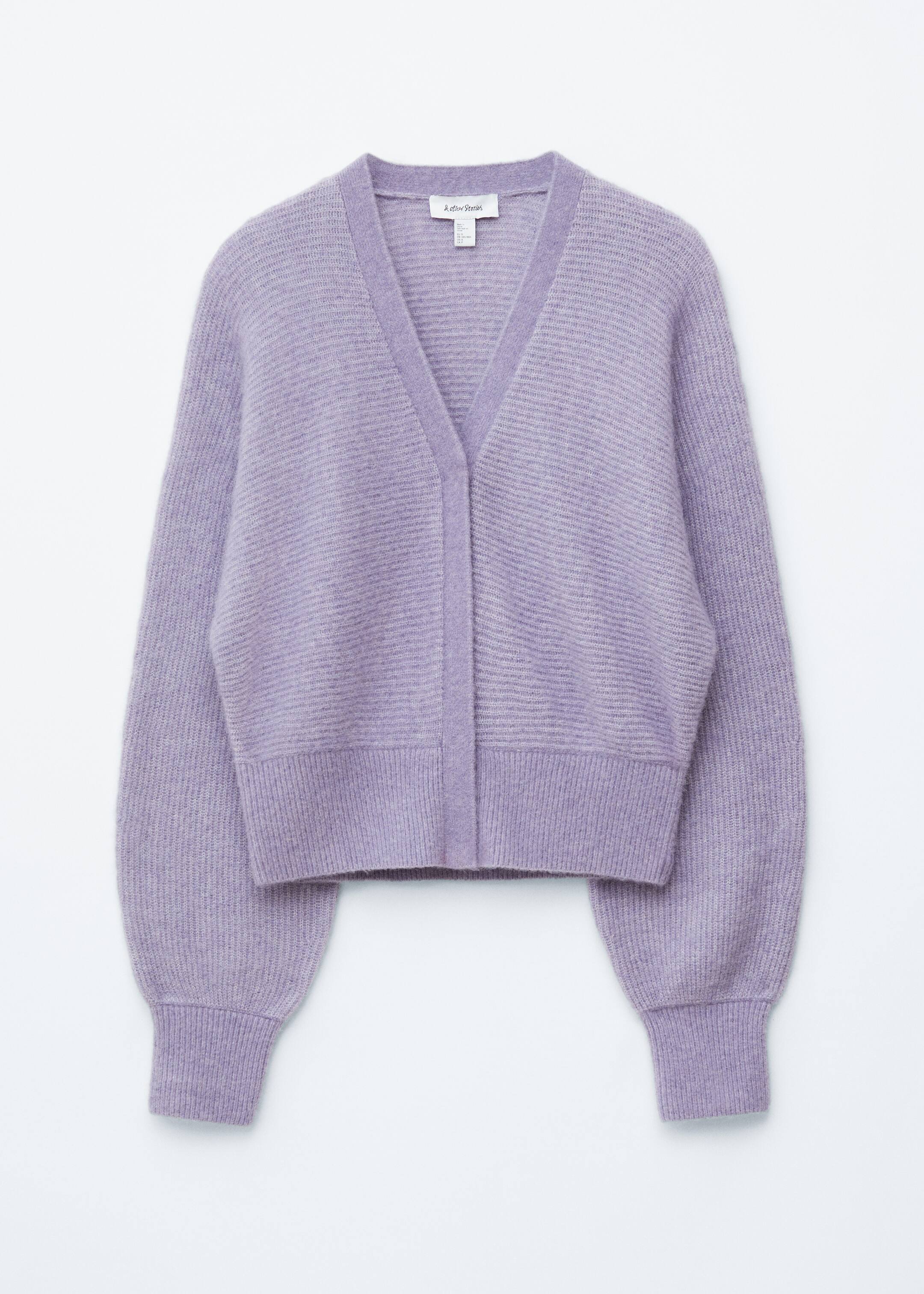 Agrandir l'image: Un cardigan court de couleur violet clair est présenté de face, avec un col en V et une texture en maille côtelée. Le corps principal et les manches longues et volumineuses présentent des côtes horizontales, tandis que les manches ont des poignets côtelés verticalement et un ourlet côtelé verticalement. Une patte de boutonnage est visible.