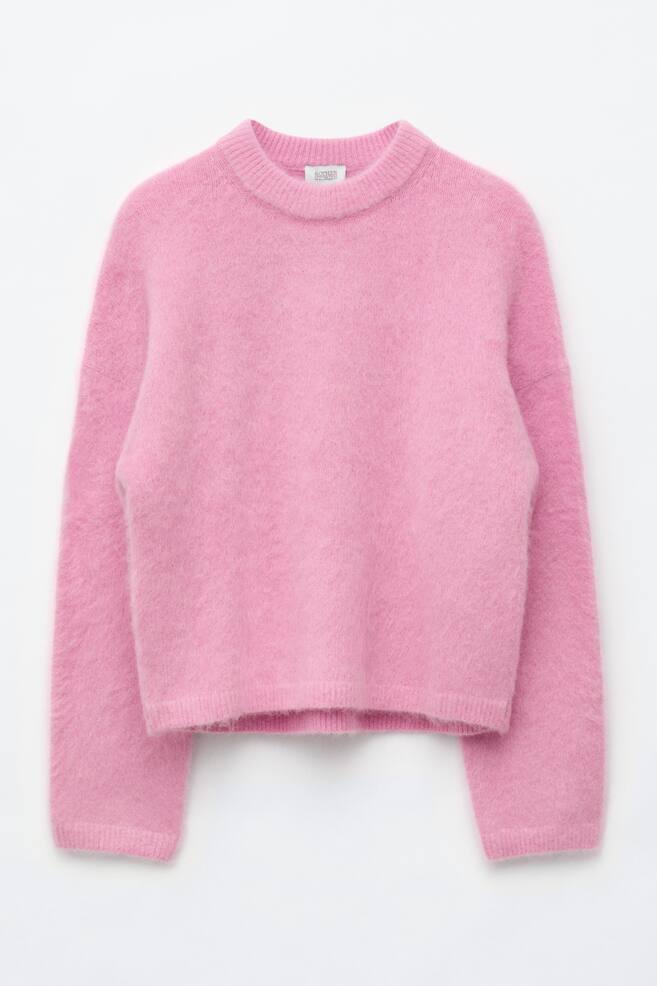 A pink mohair-blend jumper is shown from the front, with a fuzzy texture and a relaxed silhouette. It features a ribbed crew neck, dropped shoulders, and ribbed cuffs and hem. - 1