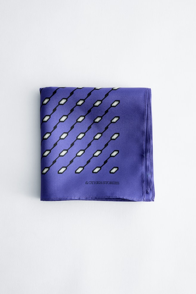 Ein violetter bedruckter Seidenschal liegt flach gefaltet mit der Vorderseite nach oben und zeigt ein diagonales geometrisches Muster aus schwarzen Linien mit kleinen weiÃen und grauen sechseckigen Formen. Der Markenname â& OTHER STORIESâ ist in Schwarz nahe der unteren rechten Ecke aufgedruckt, und der Schal verfügt über sauber vernähte, gerollte Kanten. - 1