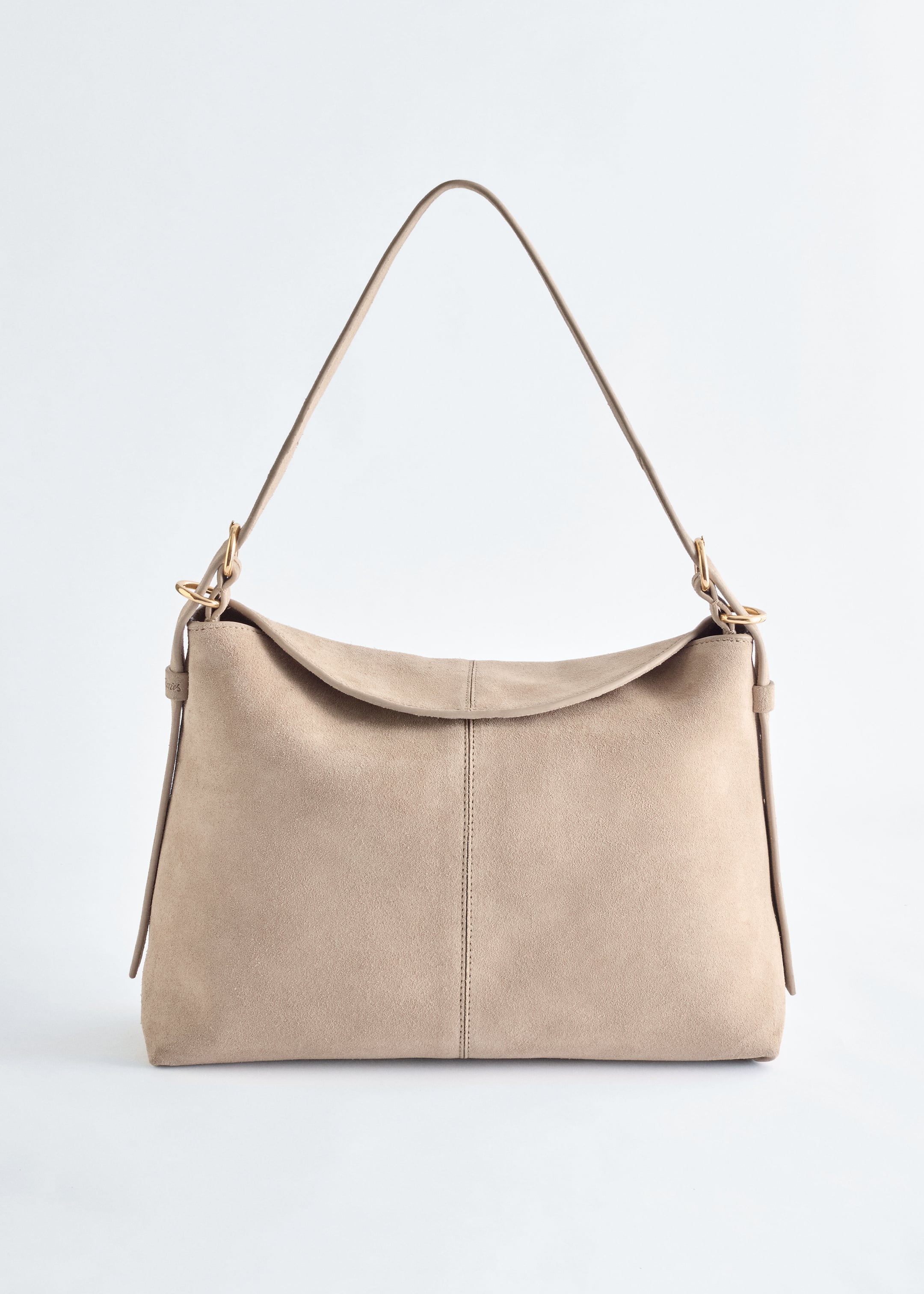 Agrandir l'image: Un sac à bandoulière beige clair en daim se tient face à vous, présentant un corps rectangulaire avec un rabat souple et incurvé et une couture verticale au centre. Une sangle ajustable est fixée avec des garnitures argentées.