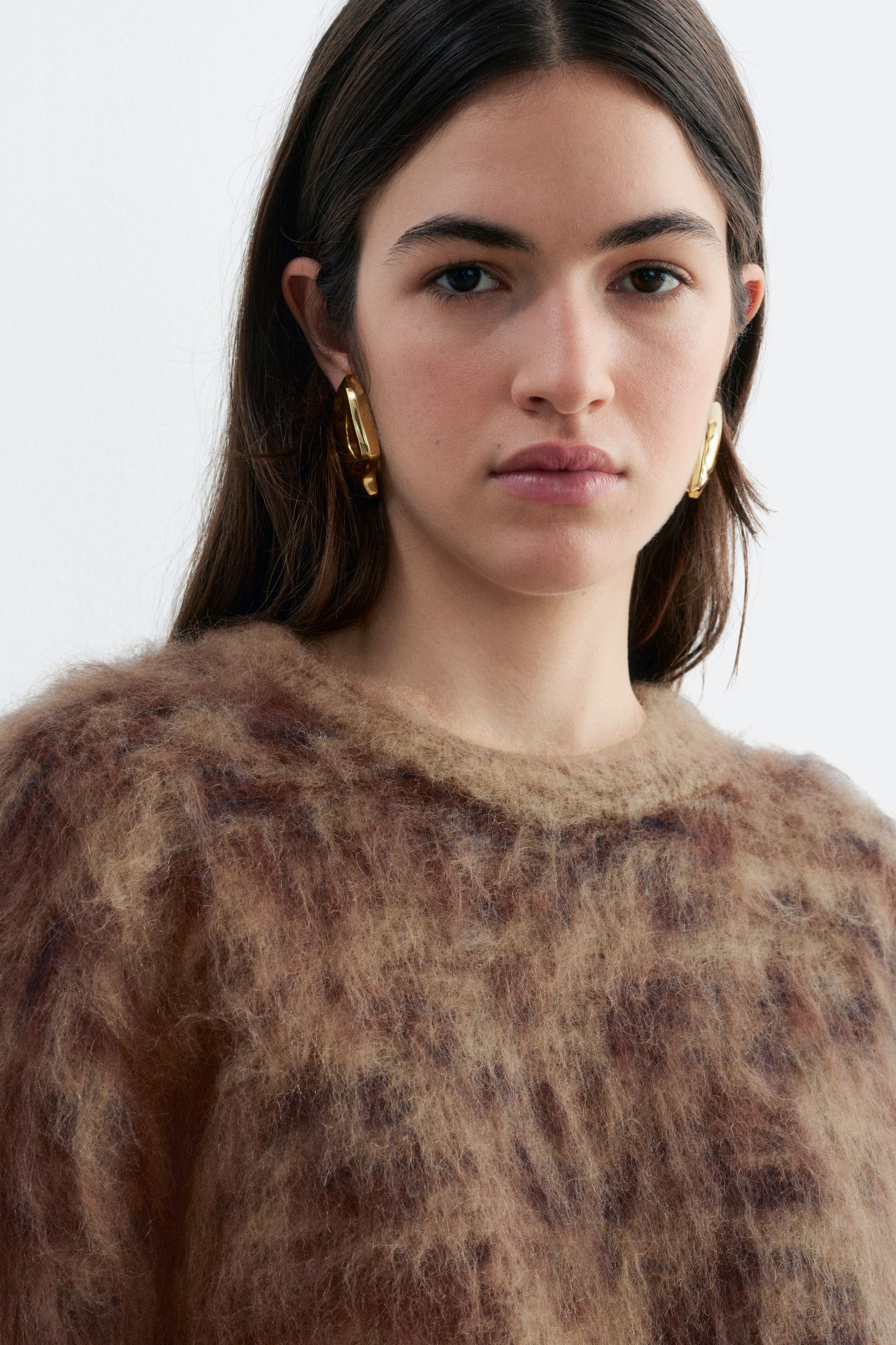 View larger image: A fuzzy mohair-blend jumper with a brown and beige brushed jacquard check pattern is being worn by the model. The jumper features a textured finish and a ribbed crew neck.