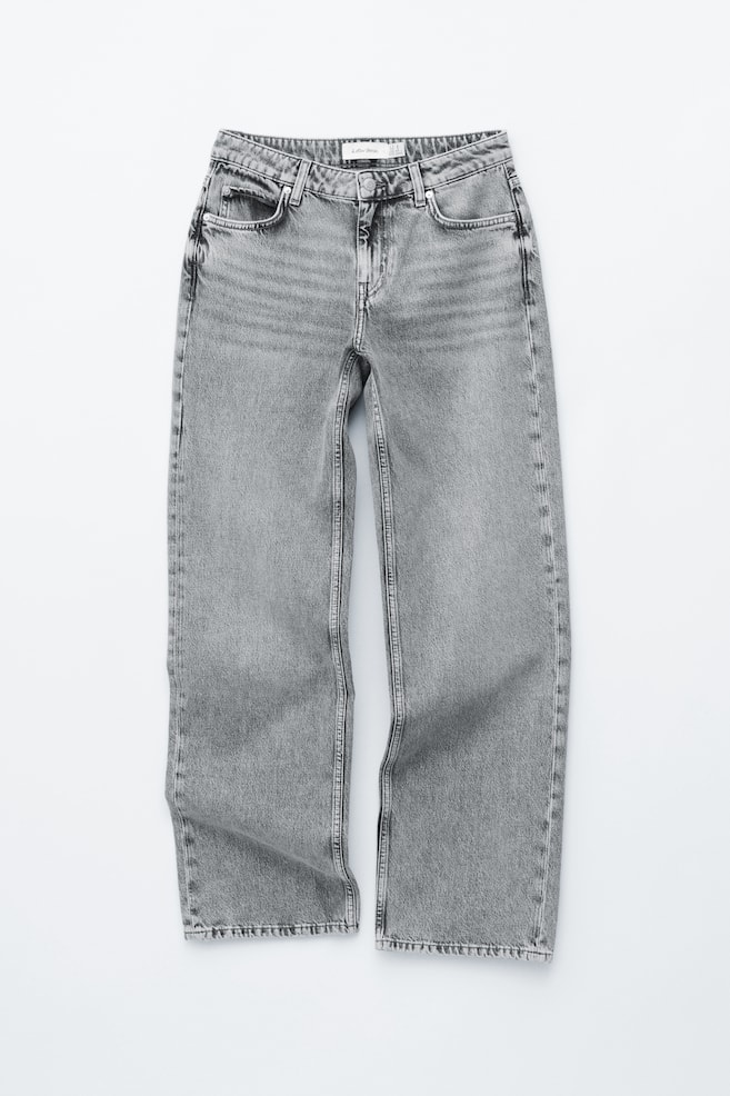 Ein Paar ausgewaschene graue Jeans liegt flach und zeigt die Vorderansicht. Sie zeichnet sich durch einen entspannten, geraden Schnitt mit Knopf- und Reißverschluss, zwei Vordertaschen, dezente Whisker-Effekte auf den Oberschenkeln und unbehandelte Beinabschlüsse aus. - 1