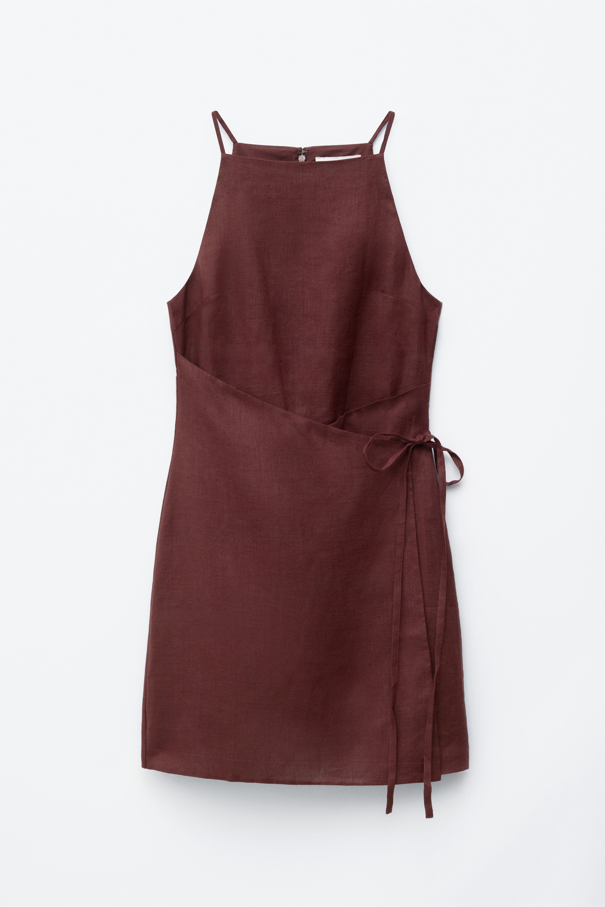 Visualizza immagine più grande: Un mini abito in lino di colore marrone rossastro scuro è presentato frontalmente, caratterizzato da un collo alto, sottili spalline e un design a portafoglio fissato da esili nastri in vita.