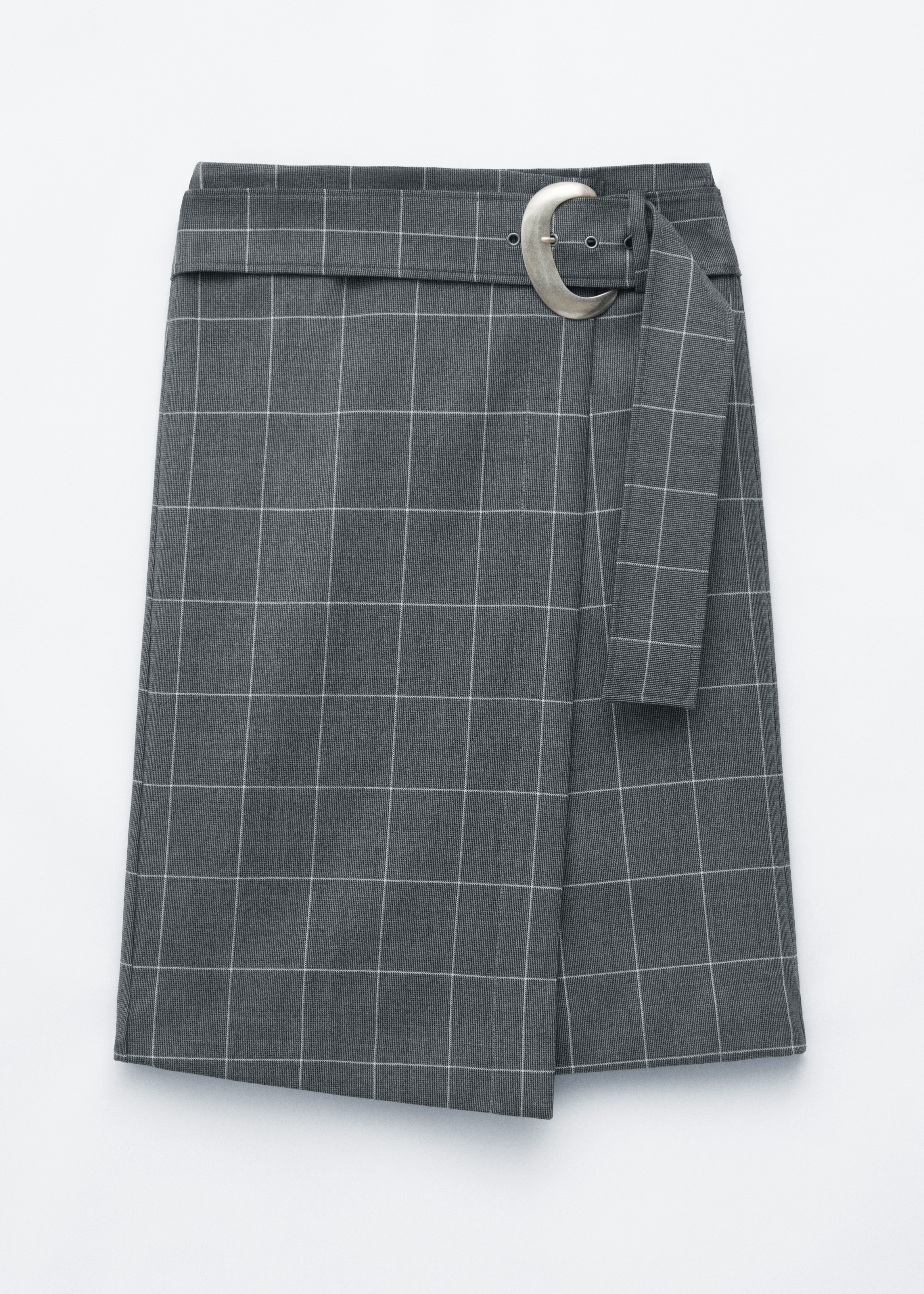 The model is wearing a grey windowpane plaid wrap-front skirt, featuring a mid-calf length and a matching belt with a large, round silver-tone buckle. The skirt is styled with a black oversized roll-neck sweater and black leather knee-high boots.