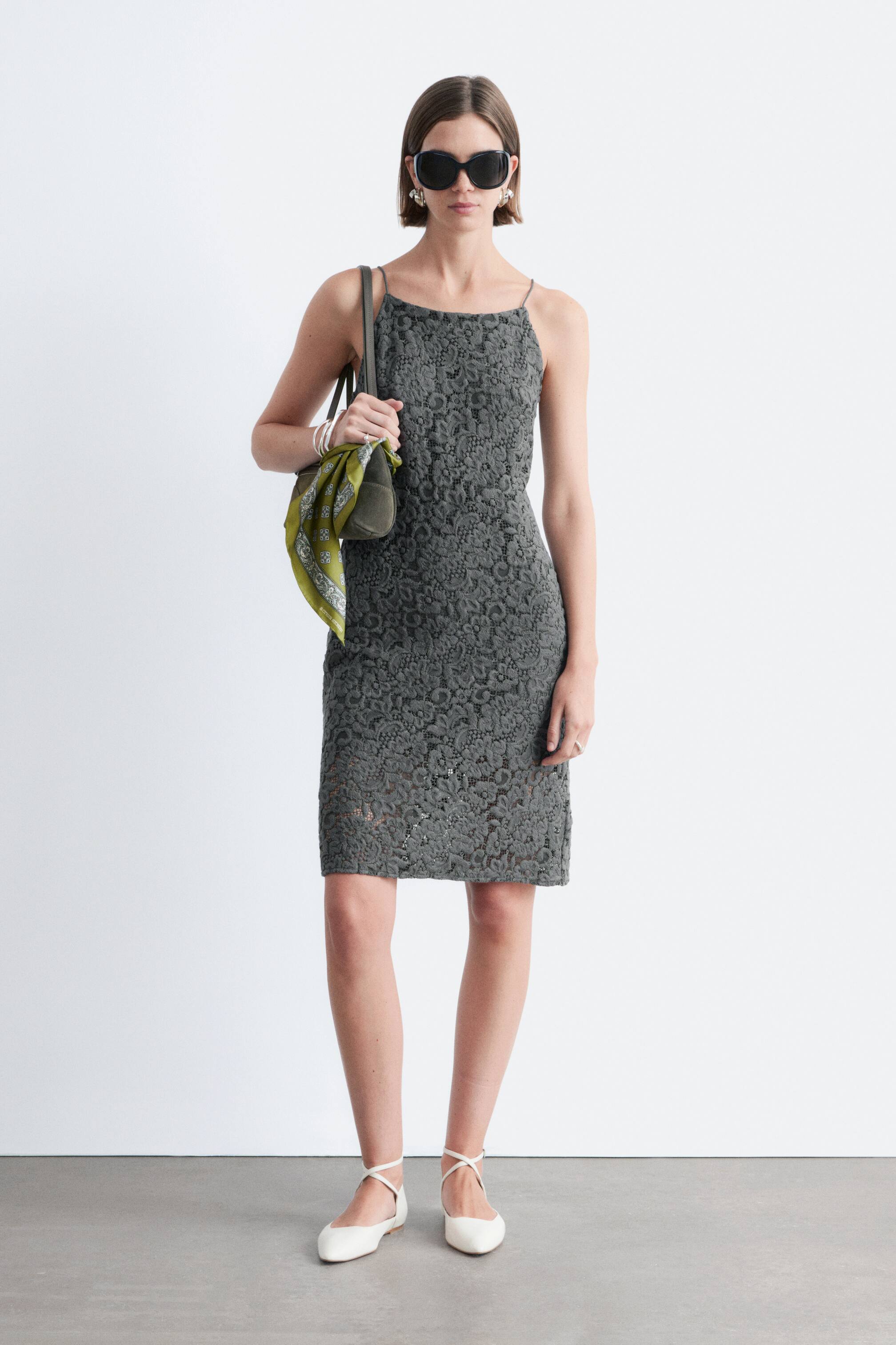 Vis større bilde: Den mørkegrå slipkjolen har en delikat blomsterblondekonstruksjon over hele. Den er designet med tynne spaghettistropper og en rett utringning, og tilbyr en tettsittende silhuett som faller over kneet.