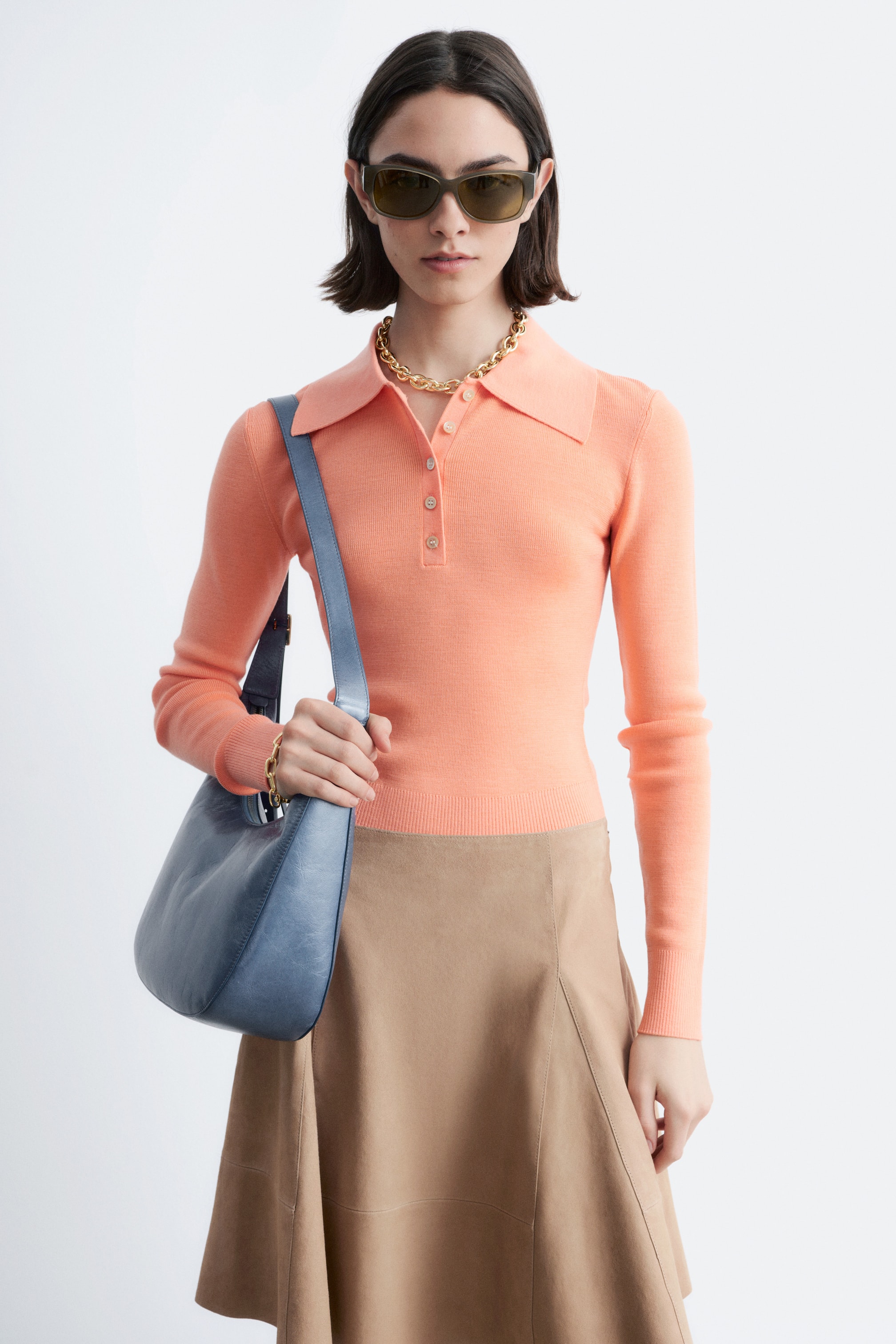 View larger image: A peach long-sleeved knitted polo shirt featuring a classic polo collar, a three-button placket, ribbed cuffs, and a ribbed hem, fitting closely to the body.