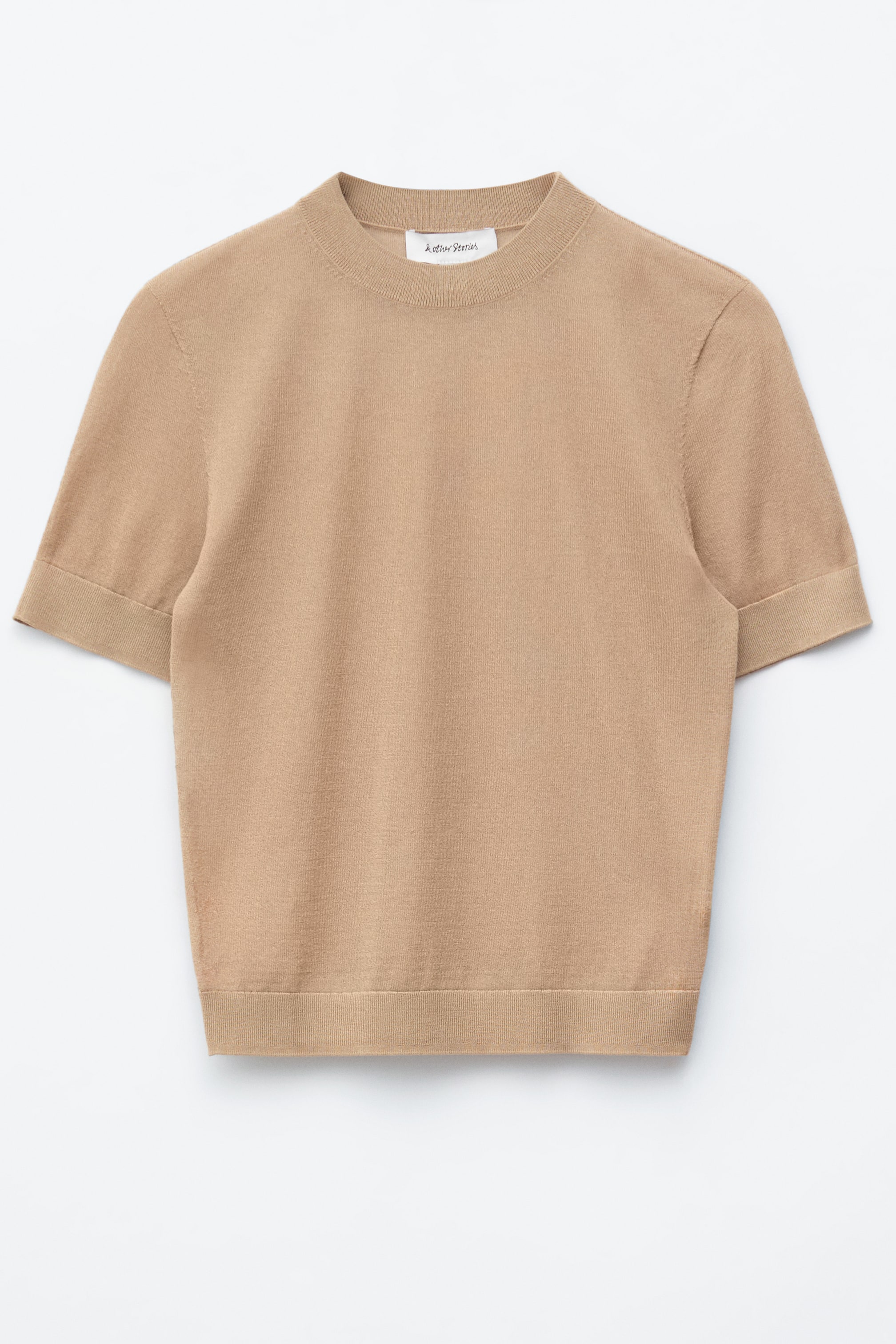 Ver imagem maior: Um top de malha castanho claro de manga curta é apresentado de FRENTE. Apresenta uma gola redonda canelada, punhos de manga curta canelados e uma bainha canelada.