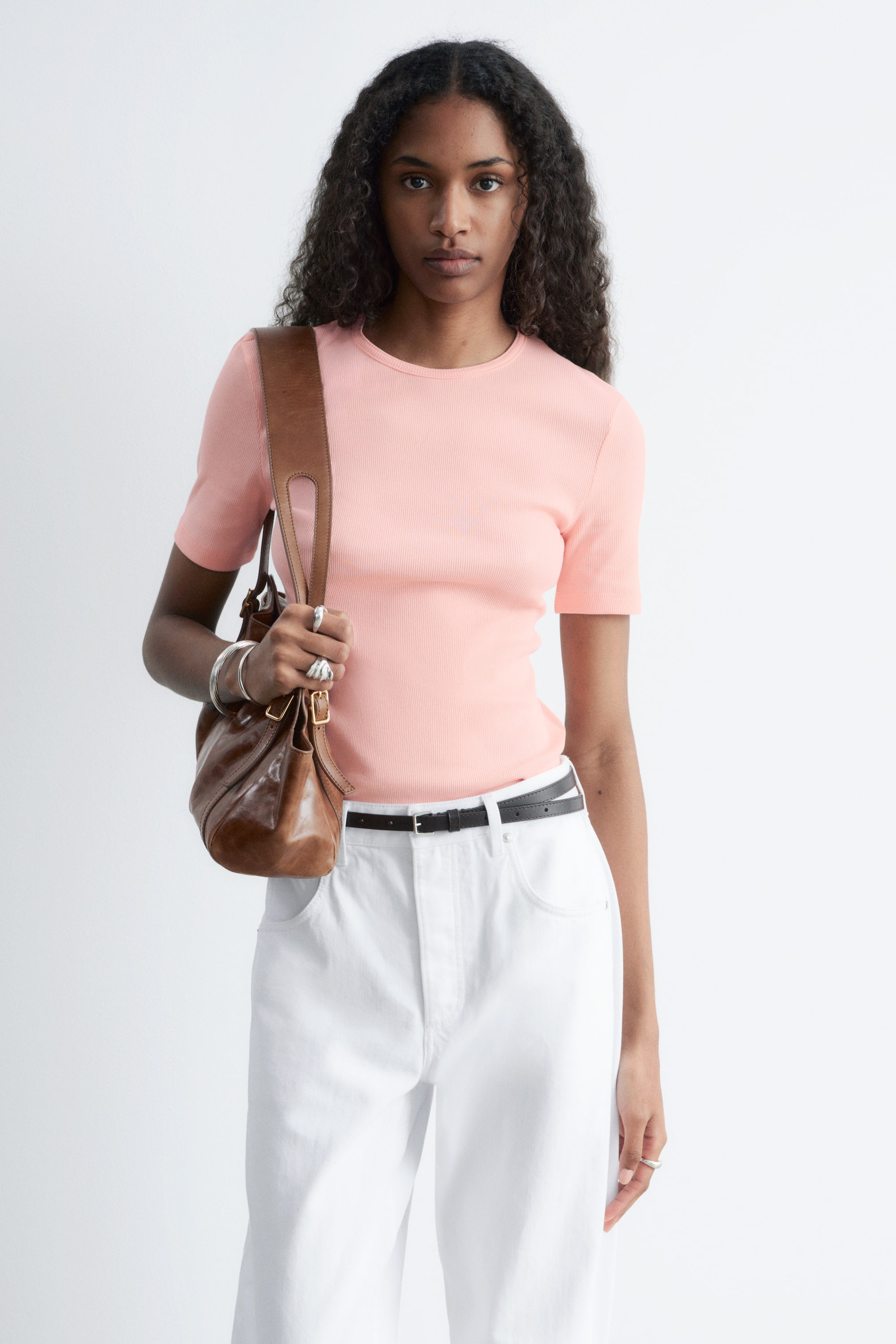 Näytä suurempi kuva: Vaaleanpunainen lyhythihainen neulepaita esitetään edestä, siinä on ribattu pinta ja pyöreä pääntie, ja se istuu tiukasti vartaloon.