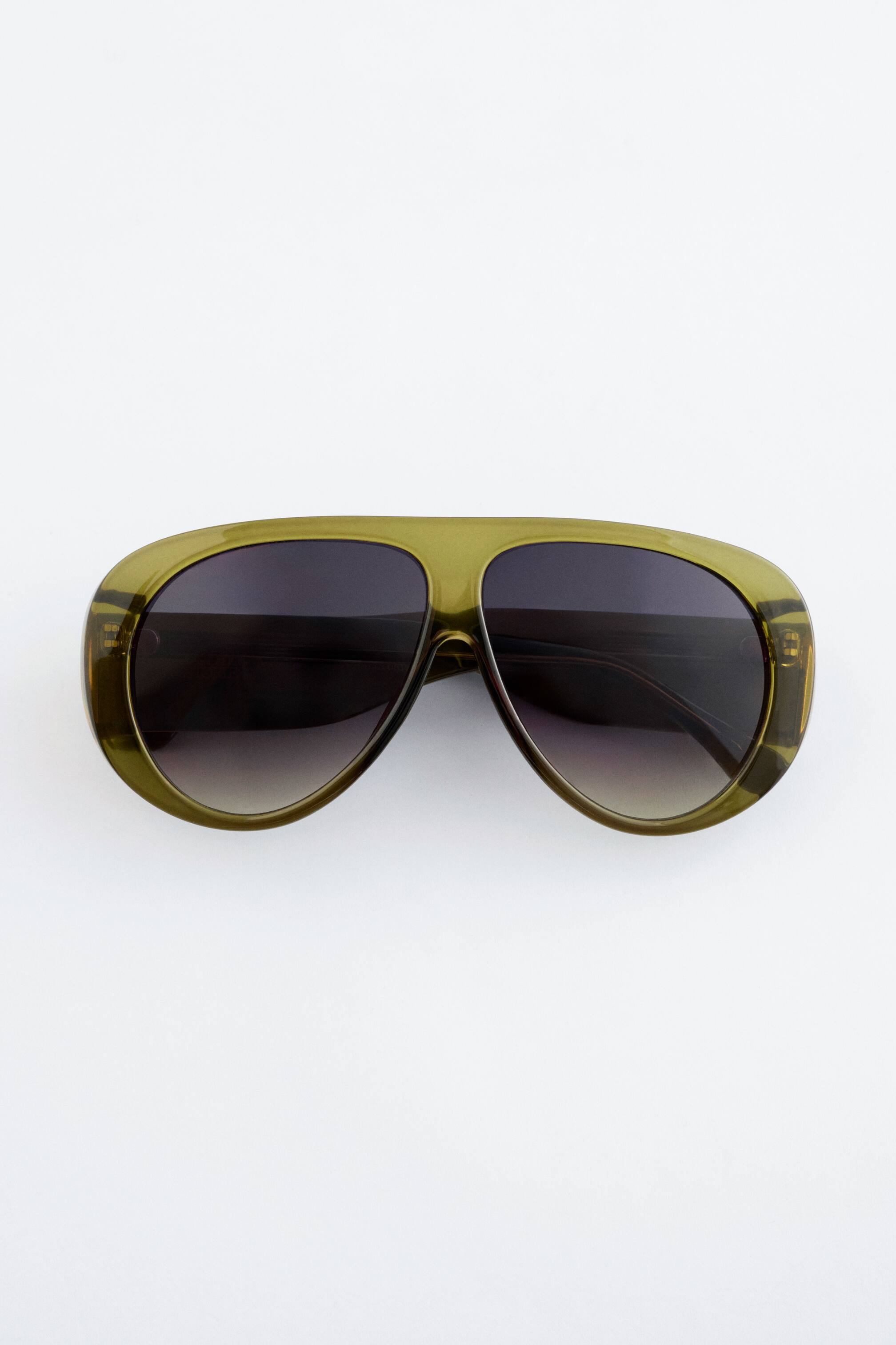 Visa större bild: Överdimensionerade aviatorsolglasögon presenteras av FRONT, med breda, genomskinliga olivgröna bågar och mörka gradienttonade linser.