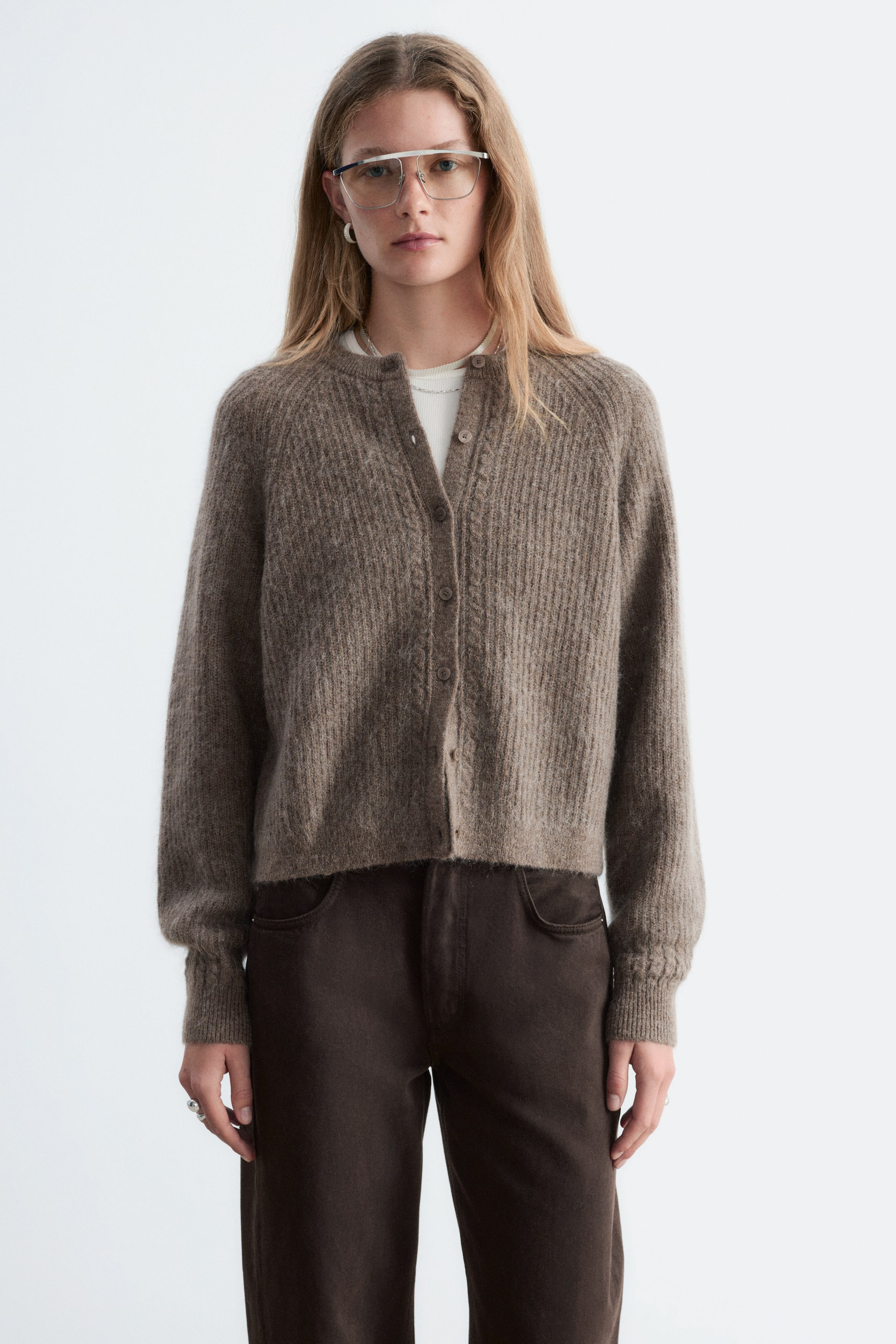 Größeres Bild ansehen: Eine braune Cardigan aus Mohair-Mix wird von vorne gezeigt und präsentiert eine entspannte Passform mit Raglanärmeln und einer durchgeknöpften Vorderleiste. Sie verfügt über vertikale Rippenstruktur, dezente Zopfstrickdetails auf beiden Seiten der Knöpfe und oberhalb der Bündchen sowie einen gerippten Abschluss an Ausschnitt, Bündchen und Saum.