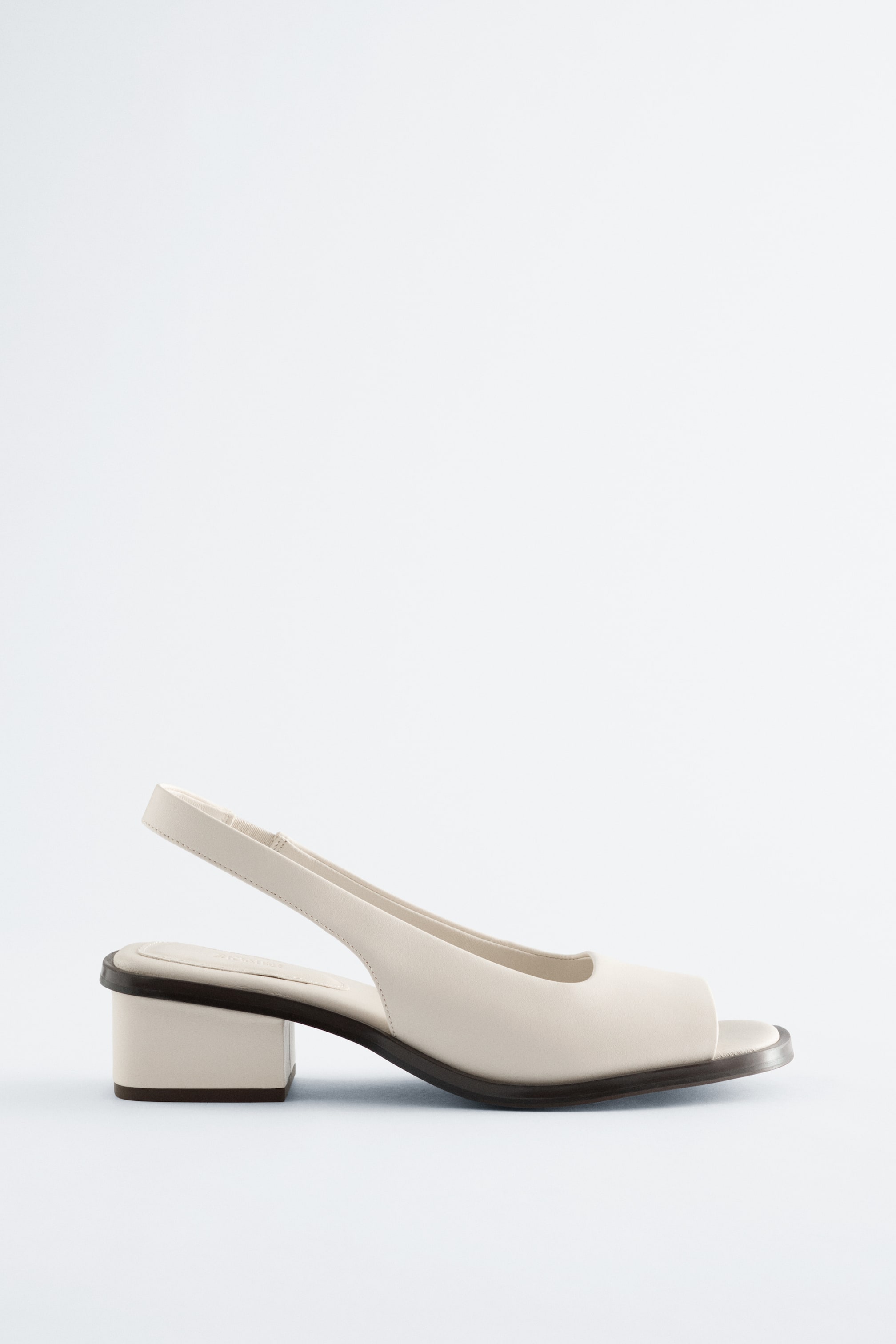 Agrandir l'image: Une chaussure slingback crème avec un bout ouvert, un talon bloc bas et une semelle marron foncé soulignant son bord inférieur.