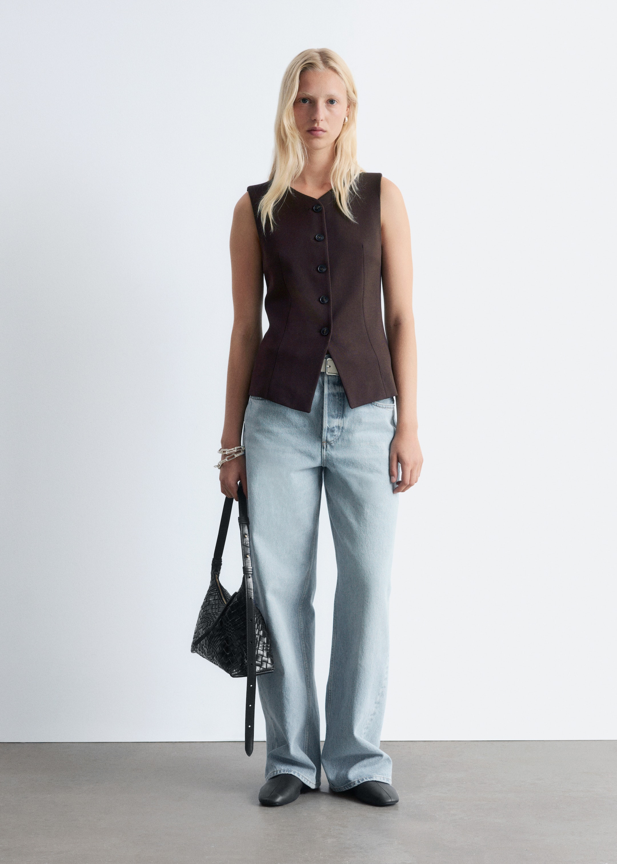 Agrandir l'image: Un gilet sans manches de couleur brun foncé est présenté de face. Il présente un décolleté en V et une fermeture à cinq boutons sur le devant, et son design ajusté est cintré à la taille et s'évase légèrement à l'ourlet.