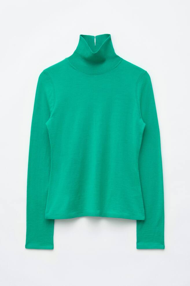 The Merino Wool Polo Neck Top is shown facing front, featuring a bright green fine-knit construction with a high, ribbed polo neck. It has long sleeves, a slim fit, and a straight hemline. - 1
