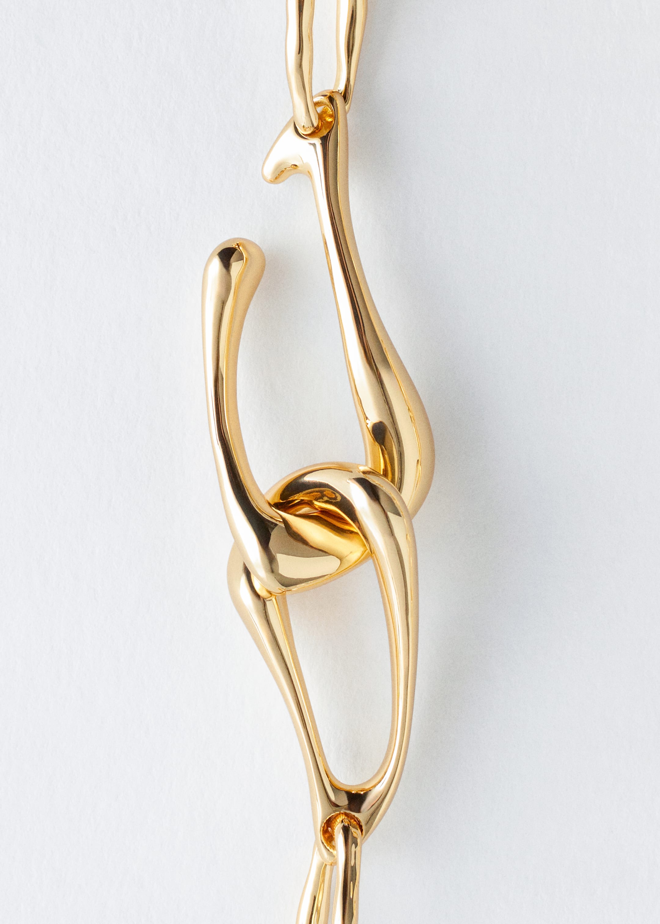 View larger image: A gold-toned necklace is showcasing its large, irregular links. An oversized hook clasp is prominently featured, connecting two of the links at the front.