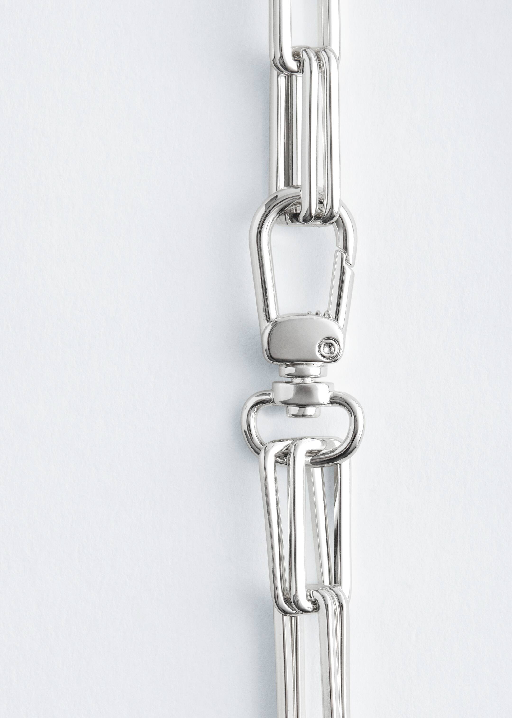 Agrandir l'image: Un collier à maillons épais de couleur argentée présente des maillons rectangulaires allongés, chacun formé de trois barres parallèles. Un grand fermoir pivotant est visible, reliant deux segments de la chaîne.