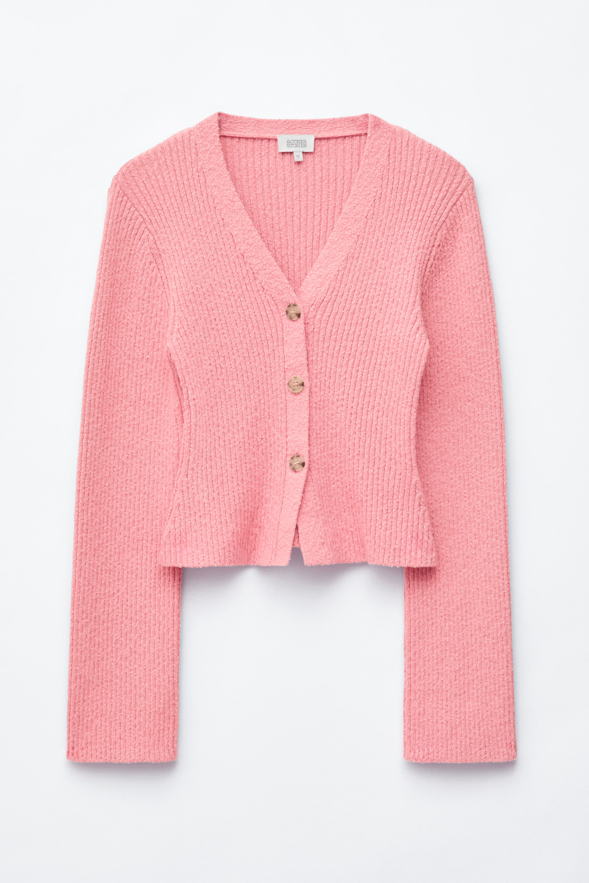 Agrandir l'image: Un cardigan rose à col en V est présenté de face, mettant en avant un tricot côtelé texturé. Une patte de boutonnage avec trois boutons marron clair descend au centre, et il affiche une silhouette ajustée et courte avec des manches longues.