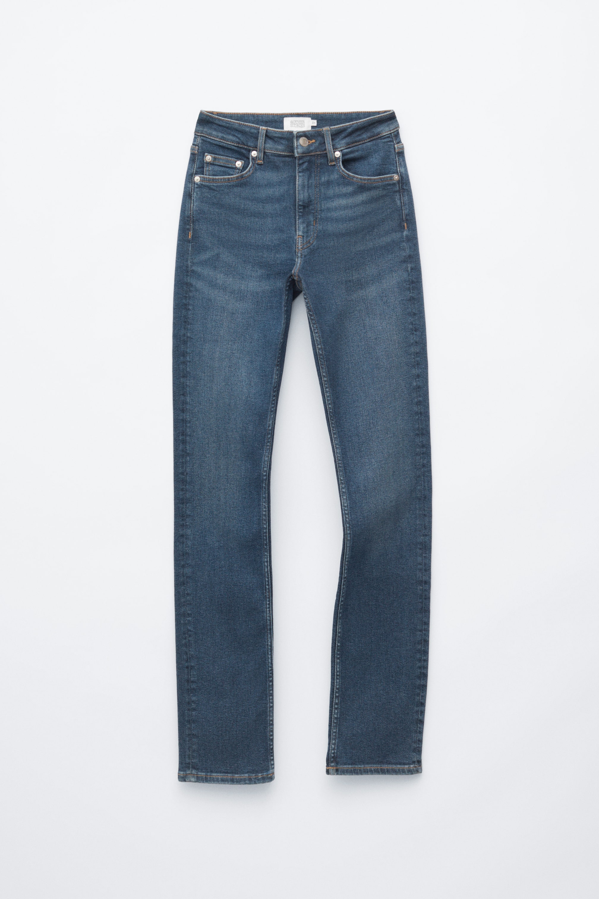 Agrandir l'image: Ce jean slim dans un délavage bleu moyen est présenté de face, mettant en avant une coupe classique à cinq poches avec des surpiqûres contrastantes dorées et des rivets métalliques. Le jean présente une taille mi-haute à haute avec passants de ceinture, une fermeture à bouton et un léger délavage le long des cuisses.