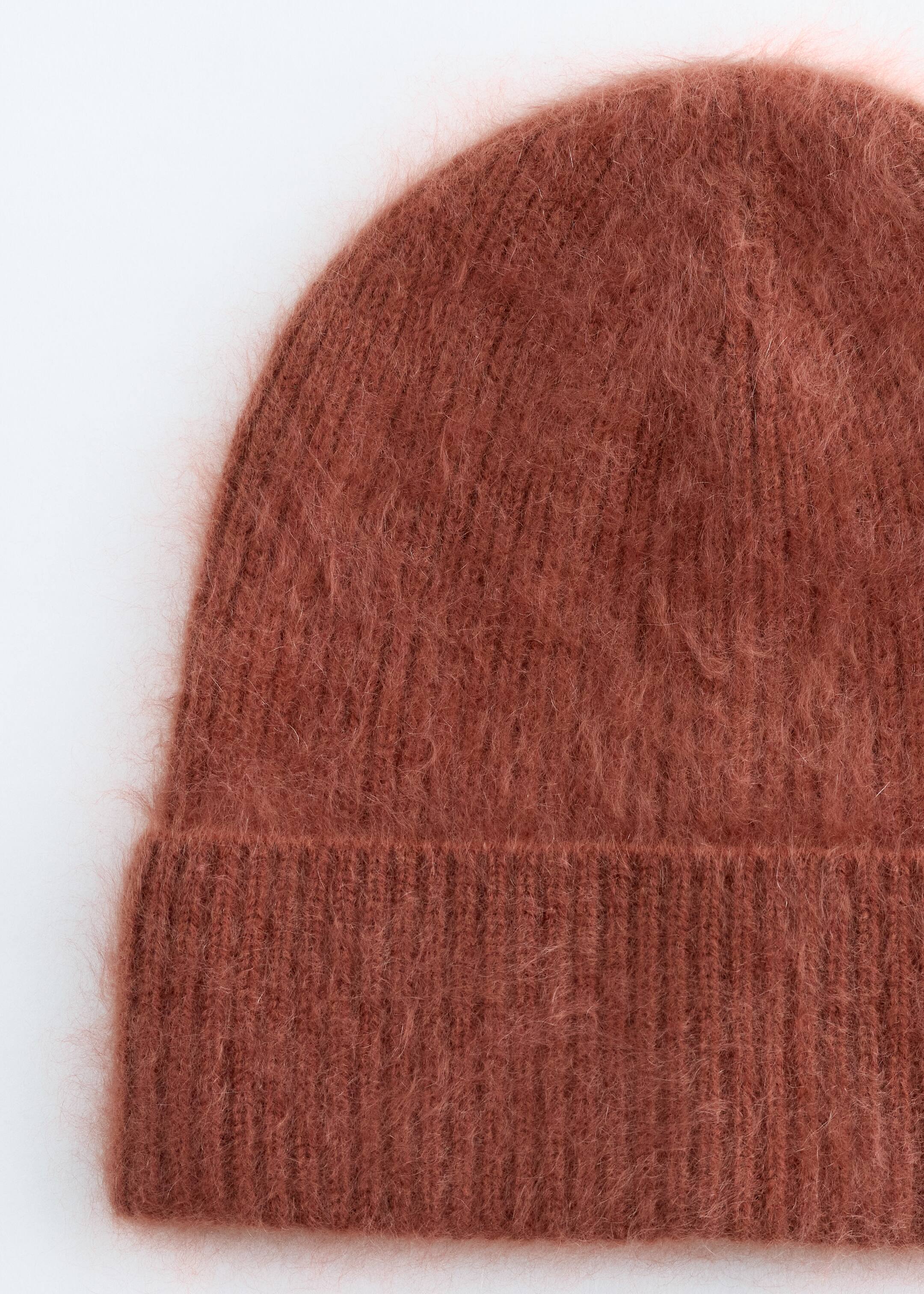 Agrandir l'image: Un bonnet brun-rougeâtre est montré de face, affichant une texture fortement brossée sur son corps principal. Il présente un revers côtelé distinct.