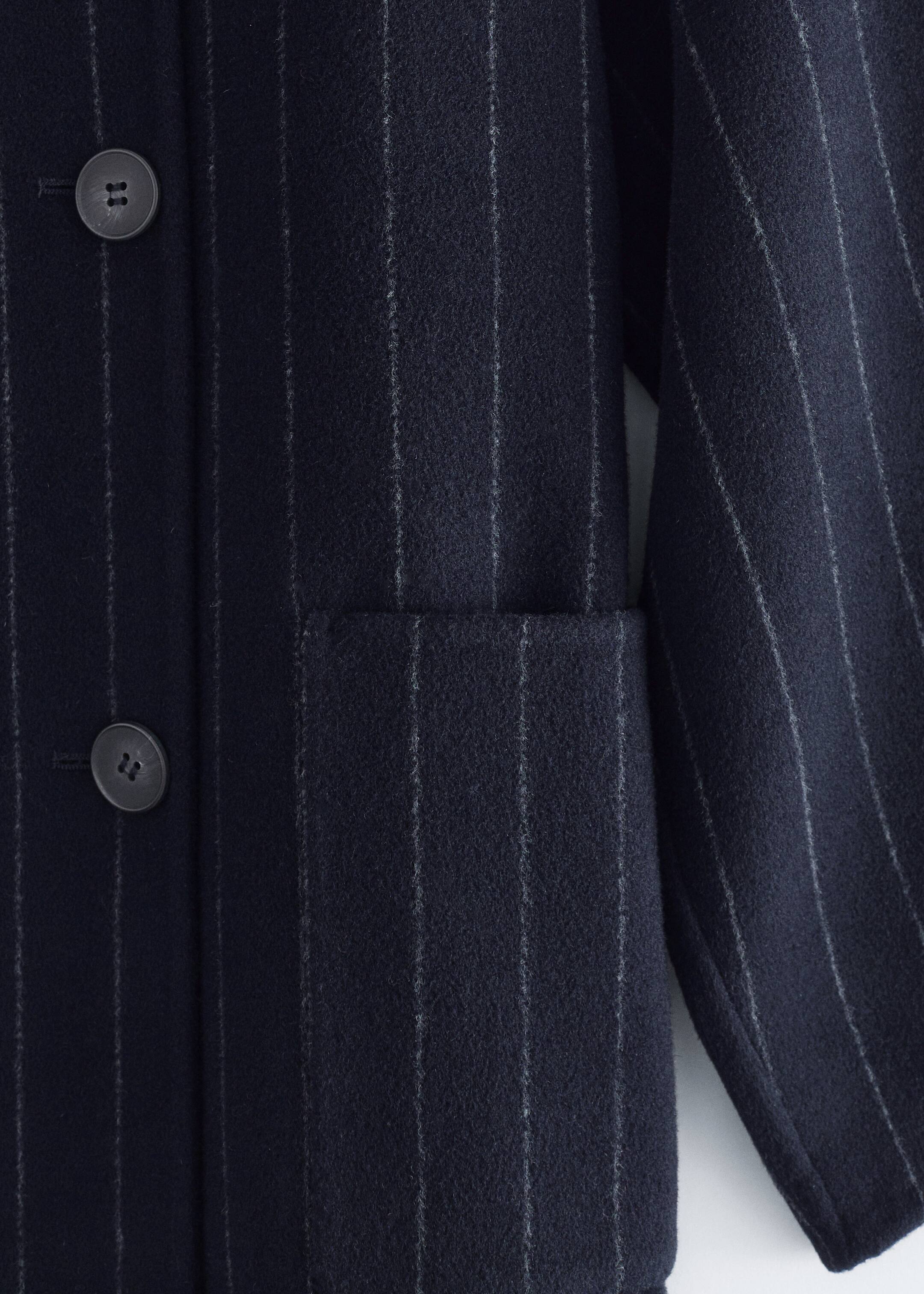 View larger image: A dark navy pinstriped jacket is being shown from the FRONT, highlighting its textured wool-blend fabric with fine white vertical pinstripes. It is featuring a dark round button and a rectangular patch pocket on its front panel, with a sleeve visible on the right.