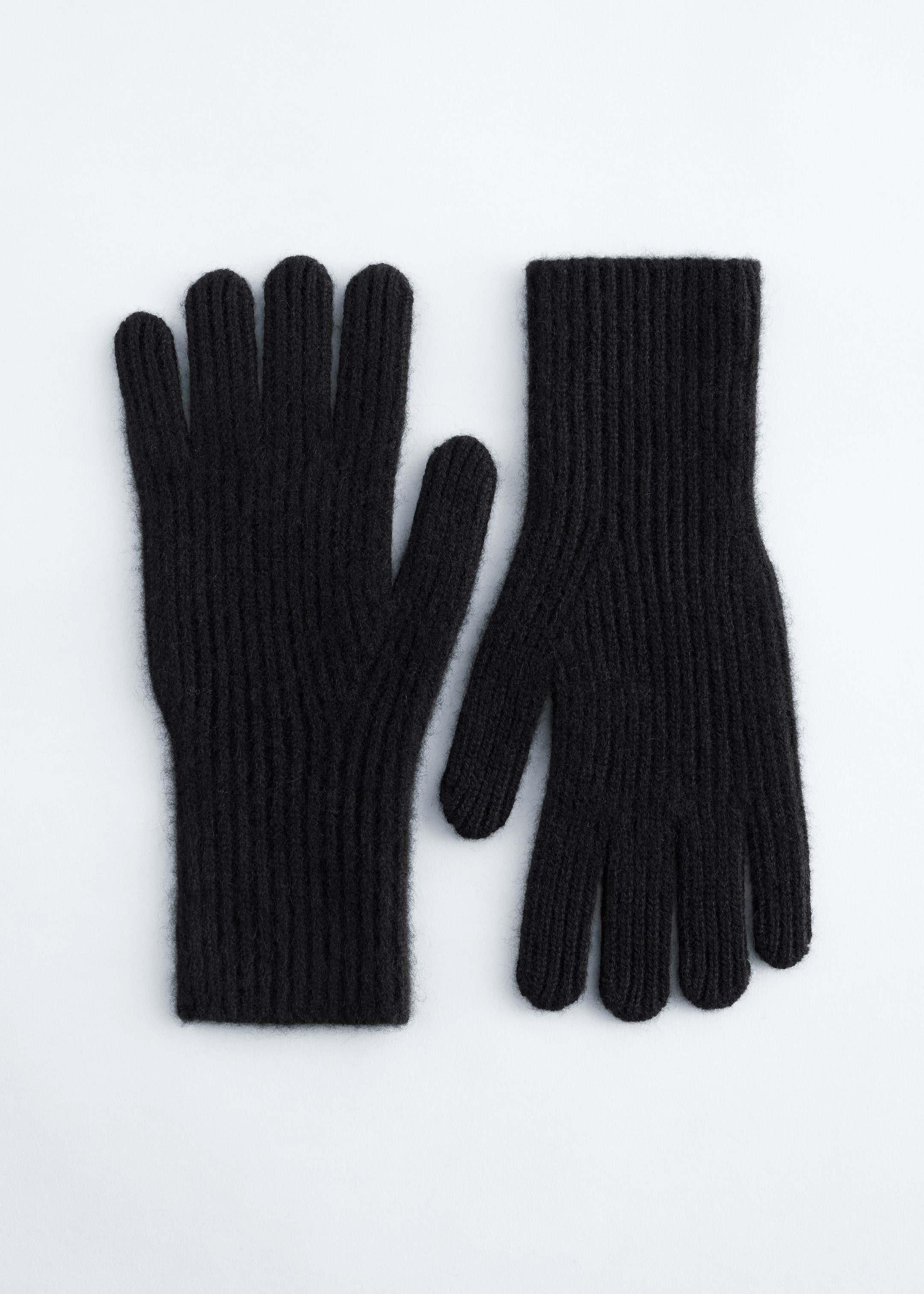 Visa större bild: Ett par svarta handskar ligger platt, framåtvända, med ett ribbstickat mönster genomgående från fingertopparna till de rakskurna muddarna.