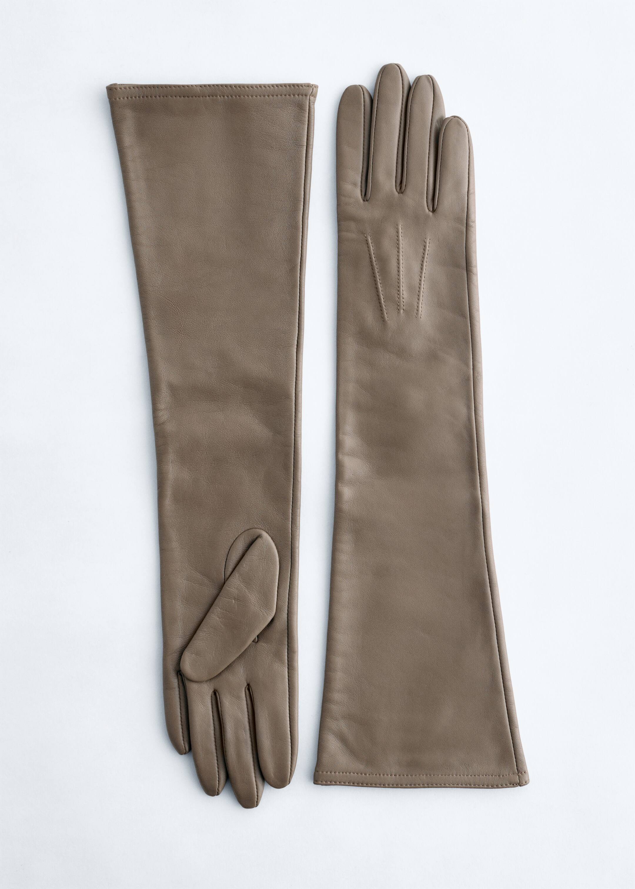Visa större bild: Ett par armbågslånga läderhandskar presenteras, liggande platt. En handske visar sin handflata med en separat tumpanel, medan den andra visar sin handrygg, detaljerad med fin dartstygn.