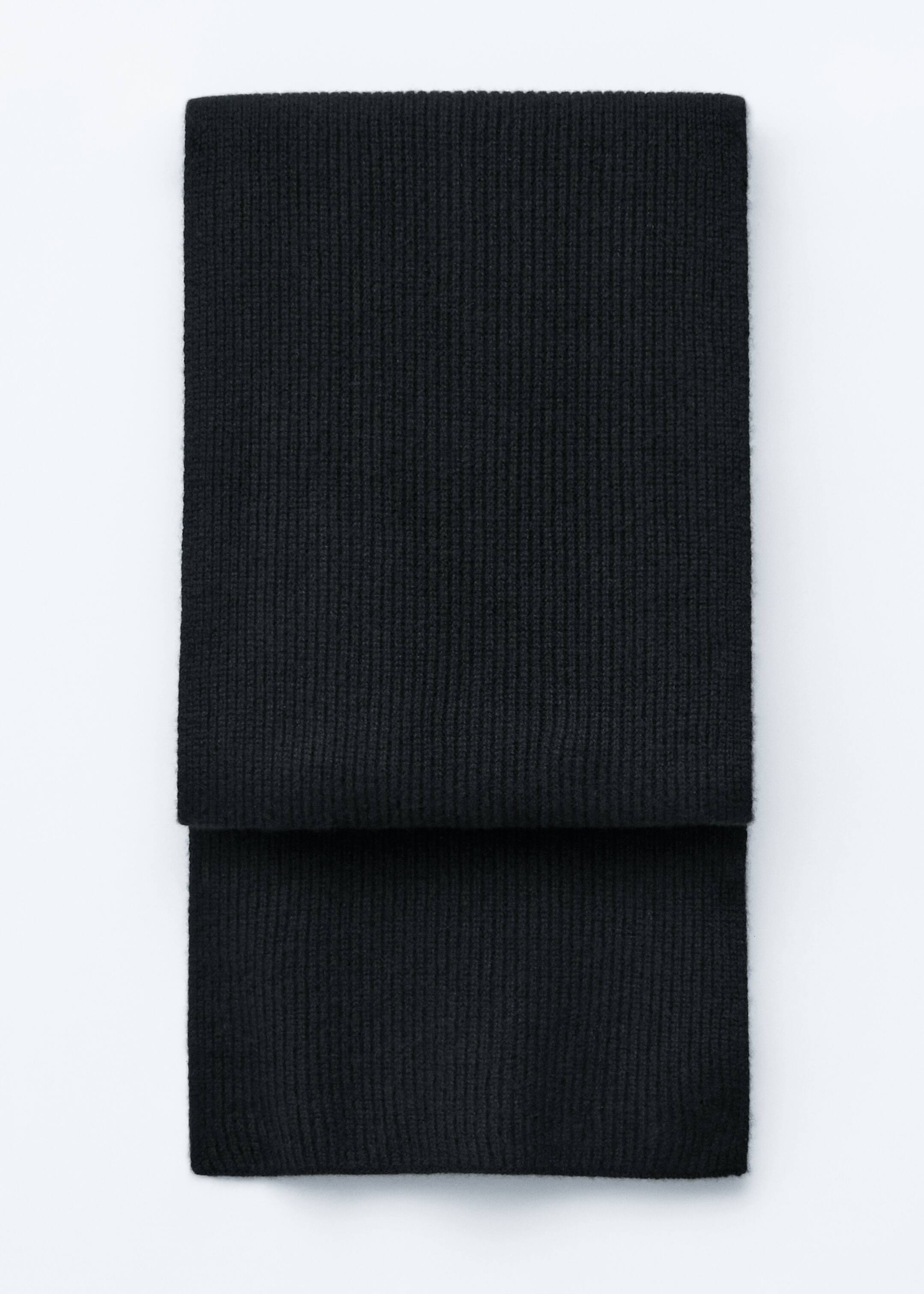 Größeres Bild anzeigen: Ein schwarzer, weicher Kaschmir-Strickschal liegt flach und wird aus einer Vorderansicht präsentiert. Er zeichnet sich durch eine markante gerippte Textur aus und ist in der Mitte horizontal gefaltet.