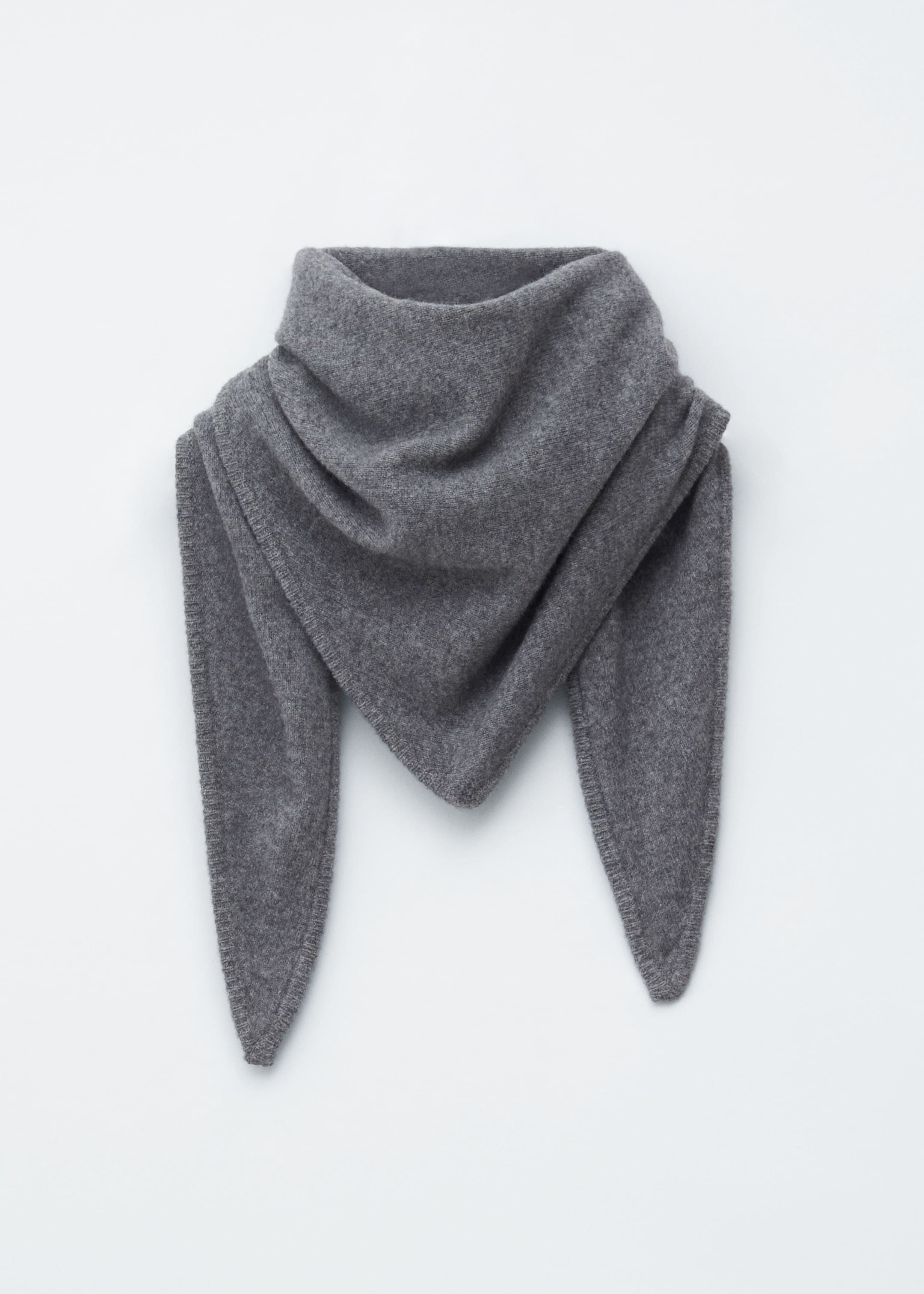 Visualizza immagine più grande: Una sciarpa triangolare grigia è presentata FRONTE, drappeggiata con la sua parte superiore che forma un voluminoso collo a cowl. Le sue due estremità appuntite pendono verso il basso e una delicata cucitura a frusta tono su tono è visibile lungo tutti i bordi della sciarpa.