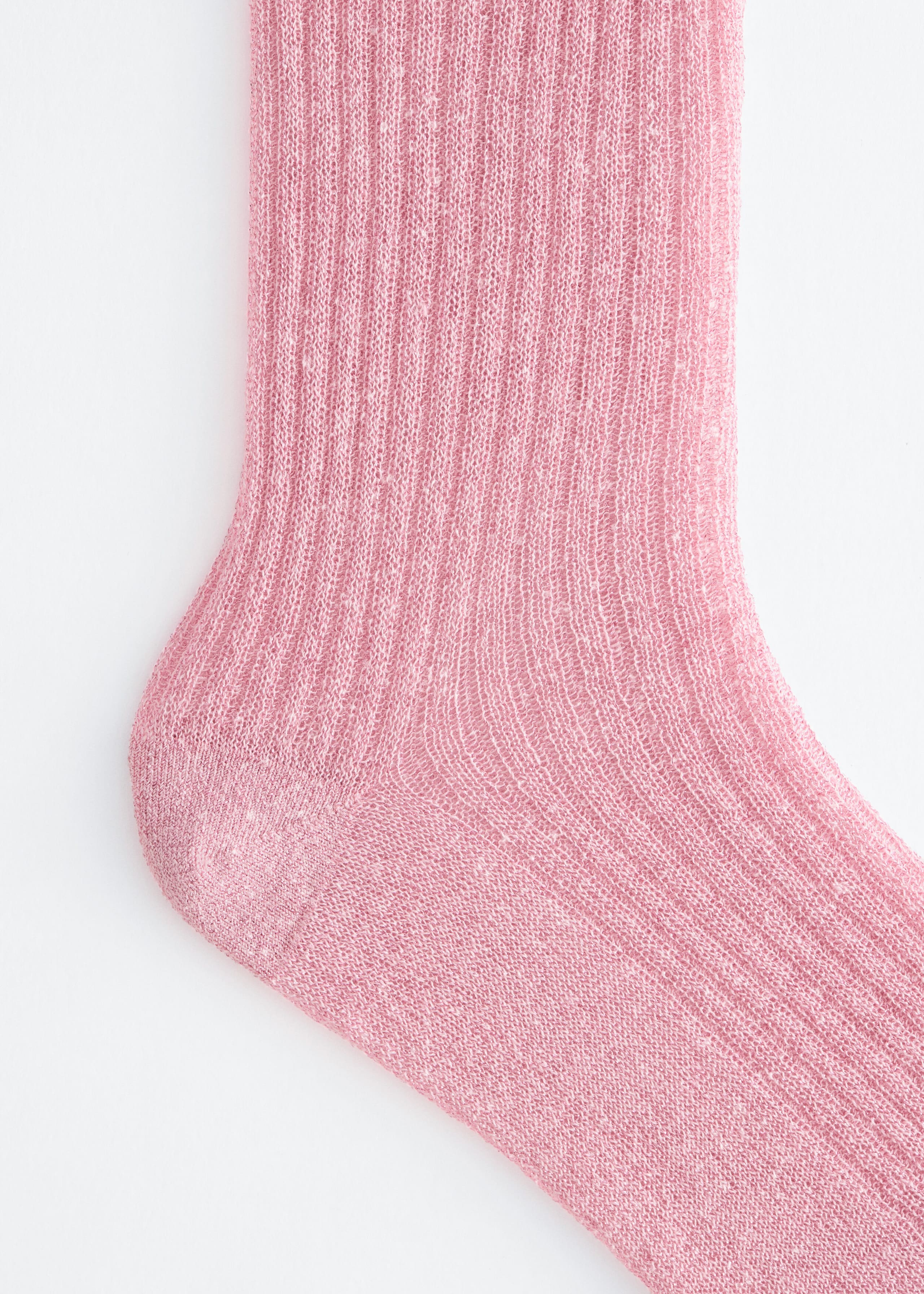 The close-up shows a light pink sock featuring a fine, semi-sheer ribbed knit texture along the leg and foot, with a smooth-knit heel cup.
