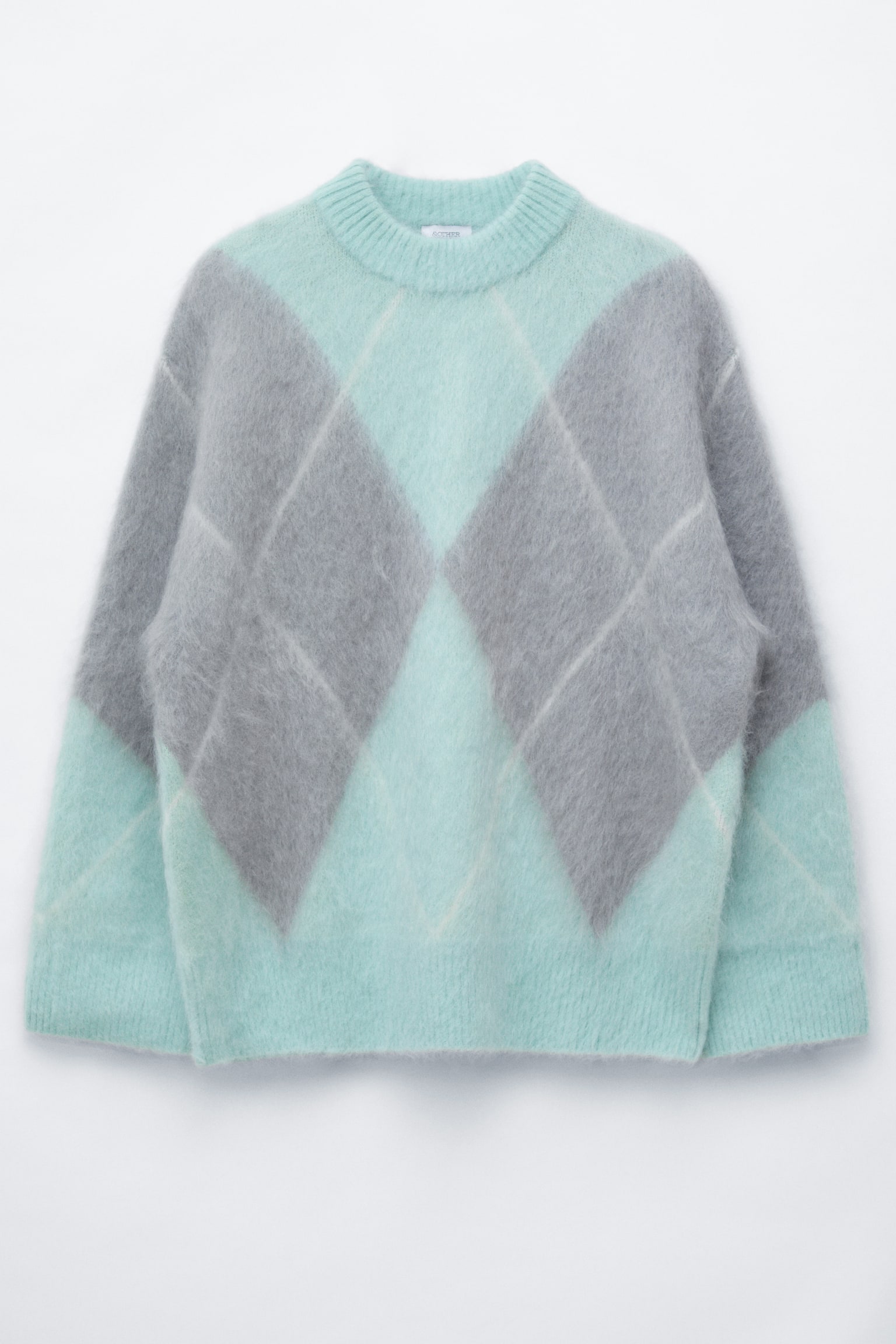 Se muestra de frente un jersey de mezcla de mohair, con una silueta oversize y un patrón jacquard de rombos en verde menta y gris. El jersey presenta un punto suave y mullido, con cuello redondo acanalado, puños acanalados y bajo acanalado.