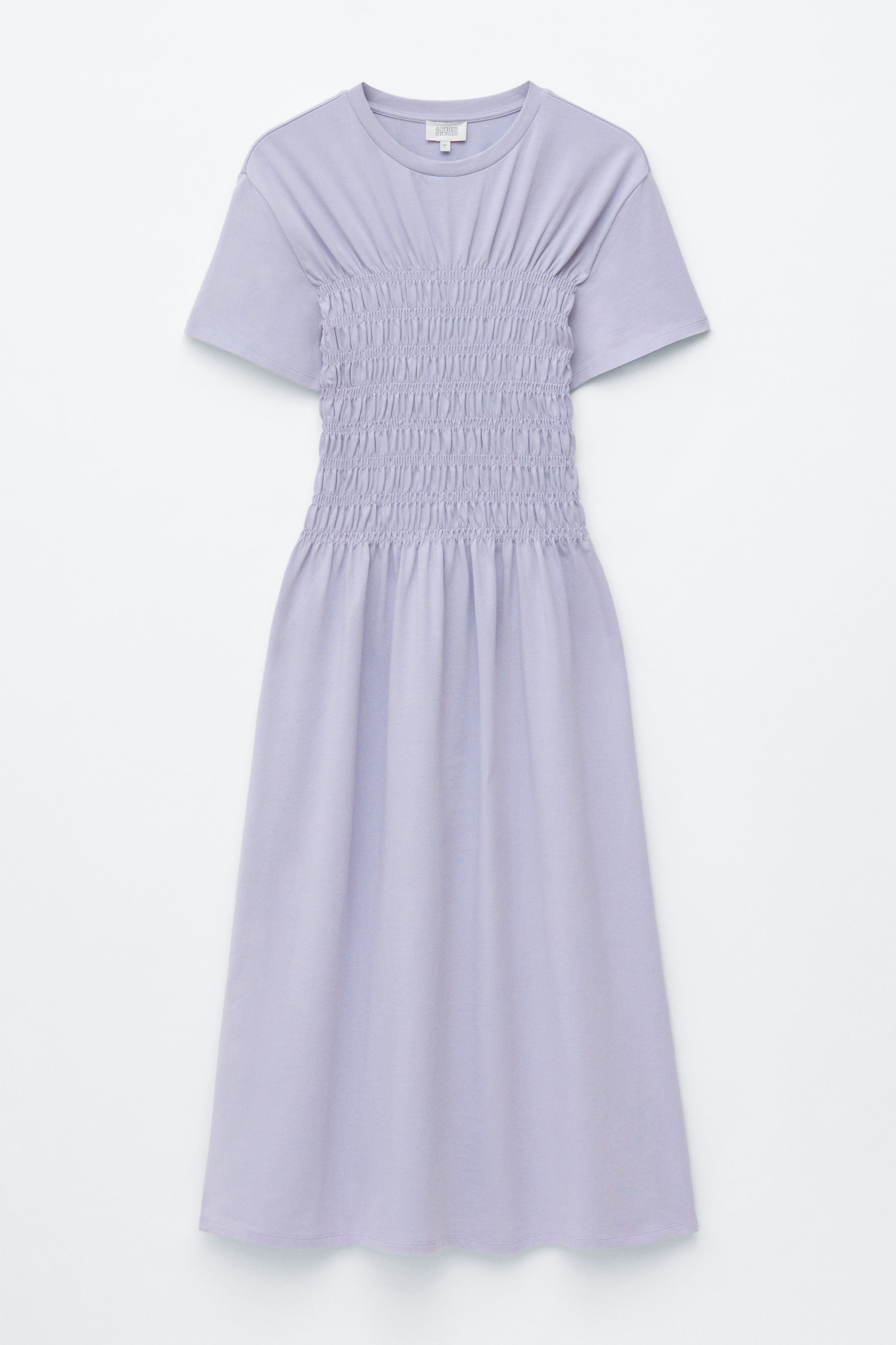 Grotere afbeelding bekijken: Een lichtpaarse katoenen jersey jurk presenteert zijn voorkant, met een ronde hals, korte mouwen en smocking in het midden, overgaand in een rok met een ontspannen pasvorm.